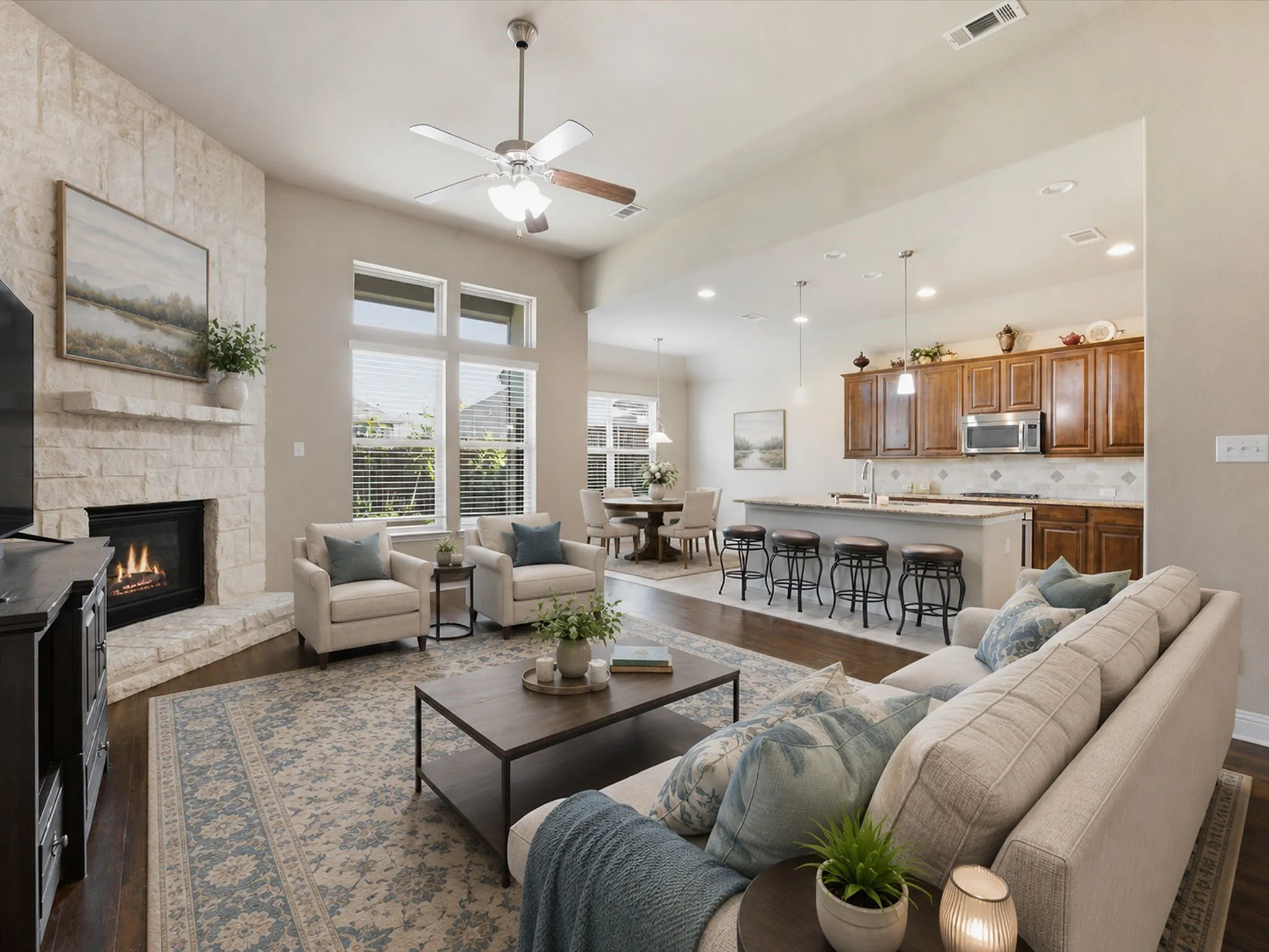 Open concept living area featuring a stone-clad fireplace and wood-finish flooring