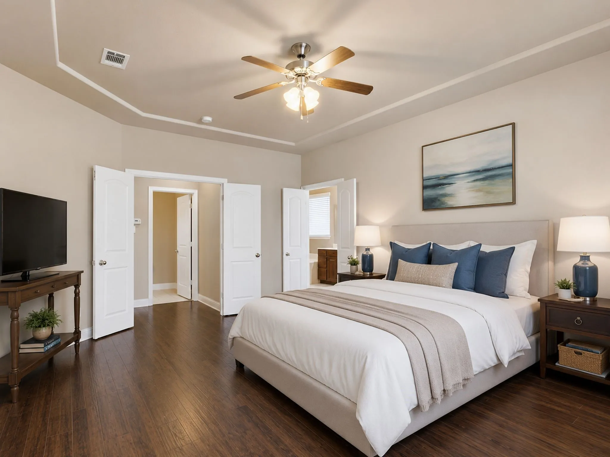 Master bedroom featuring a coffered ceiling with recessed lighting and ceiling fan, wood-finish flooring throughout, multiple white panel doors providing access to adjoining spaces, and a wall-mounted sconce beside the bed