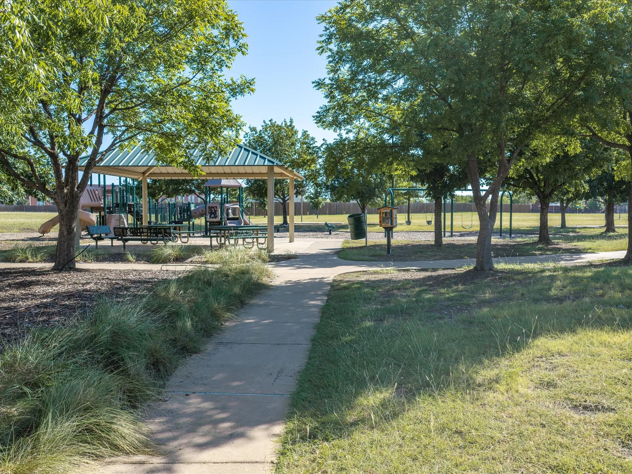Community park area featuring a covered picnic pavilion, playground equipment, and mature trees