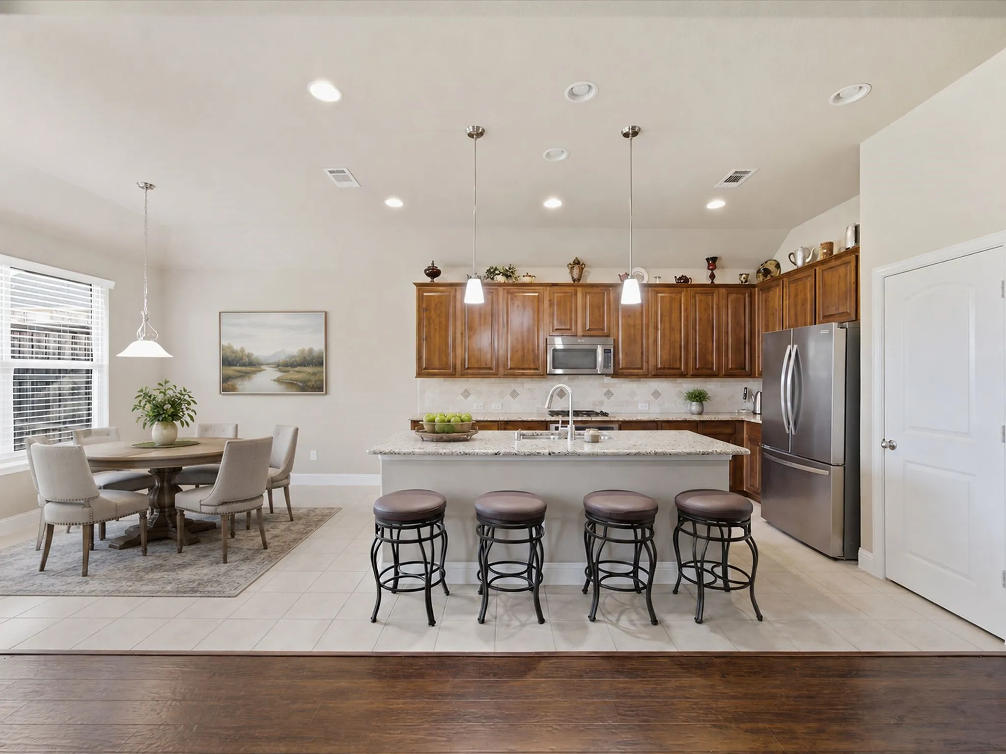 Open-concept kitchen and dining area featuring recessed lighting, a kitchen island with pendant lighting, stainless steel appliances, and wood-finish cabinetry