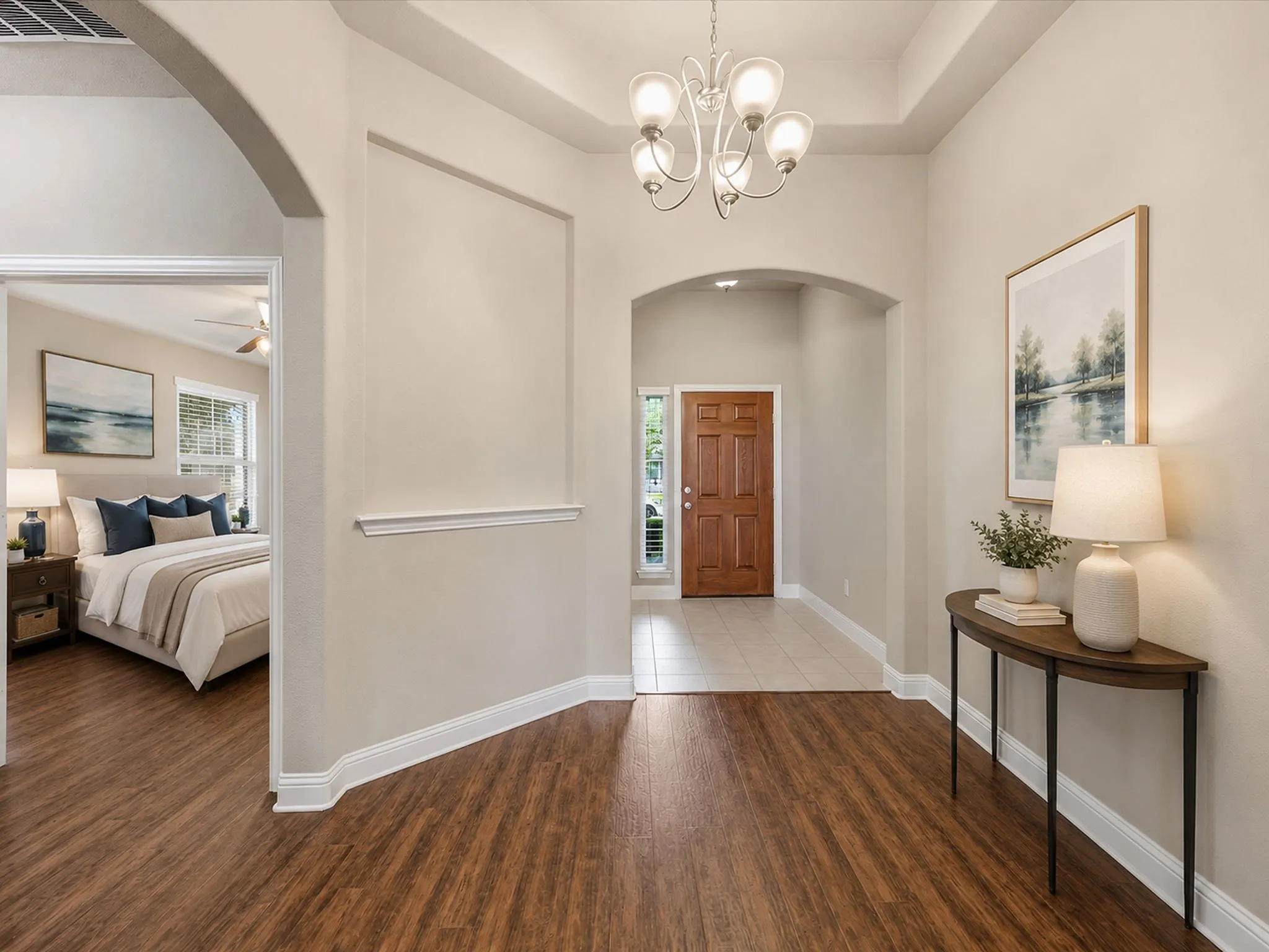 Arched doorway, wood-finish flooring, tray ceiling, chandelier, and a solid wood entry door