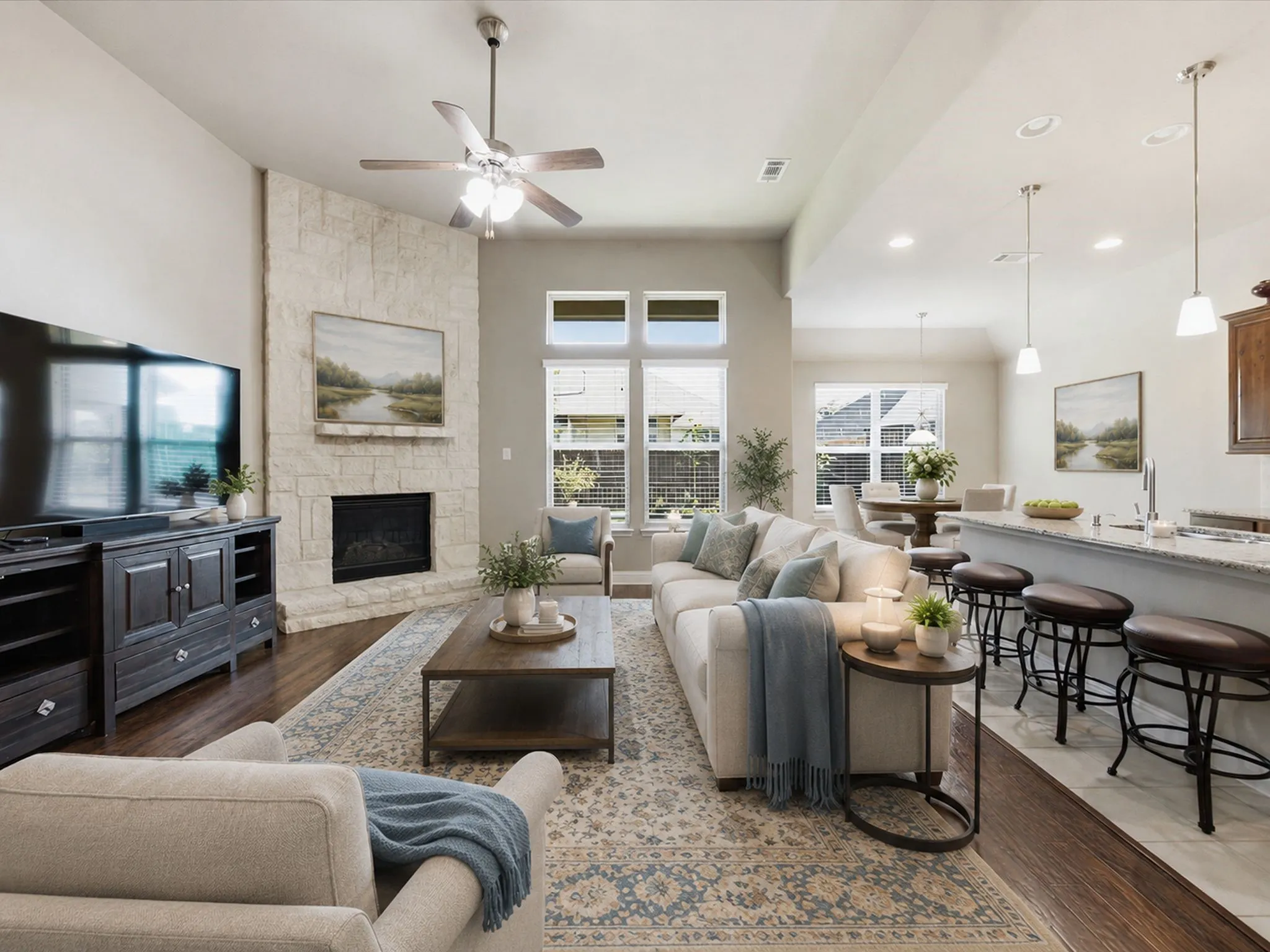 Spacious living area featuring a stone-clad fireplace, wood-finish flooring, and multiple windows