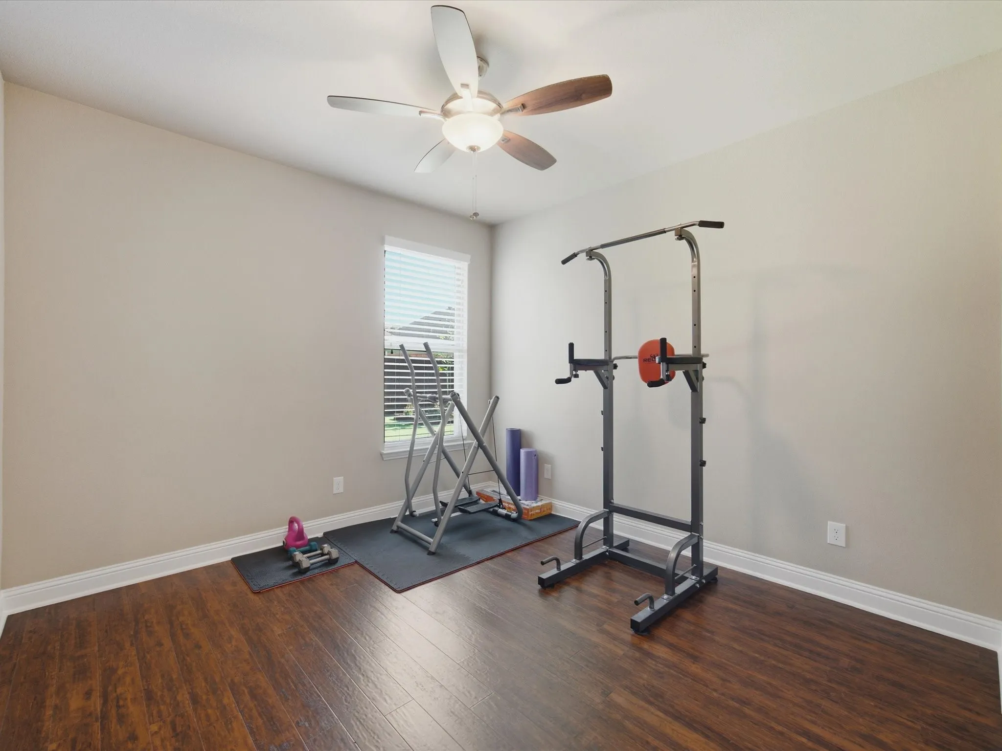 Wood-finish flooring, neutral wall tones, a ceiling fan with integrated lighting, and a window with horizontal blinds