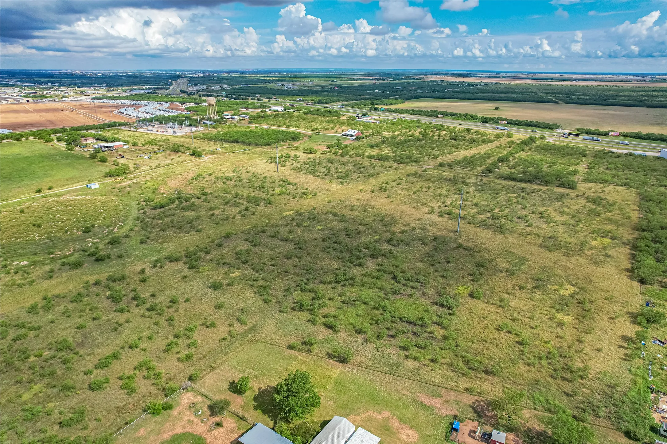 Expansive land parcel featuring natural vegetation and proximity to roadways
