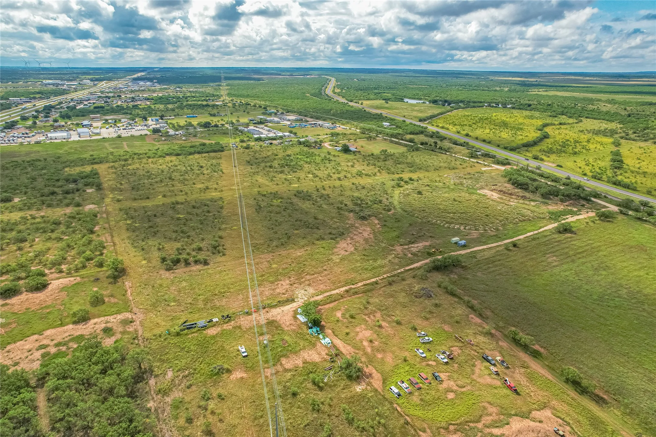 Expansive rural landscape featuring a highway, established infrastructure, and varied vegetation