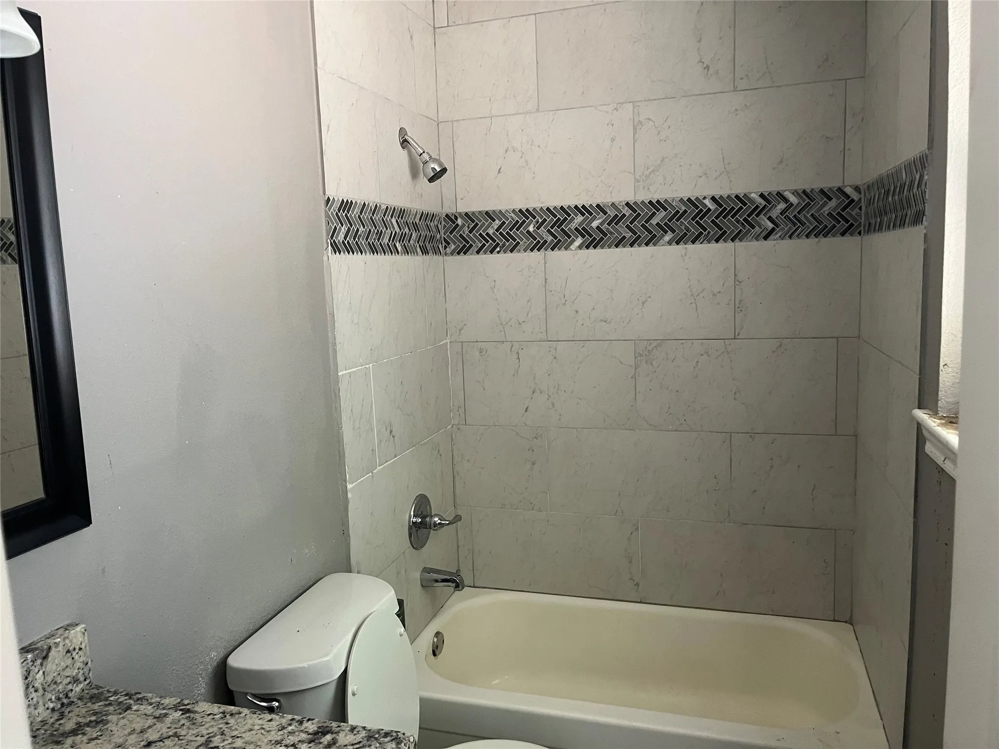 Tiled shower surround with a decorative chevron mosaic accent