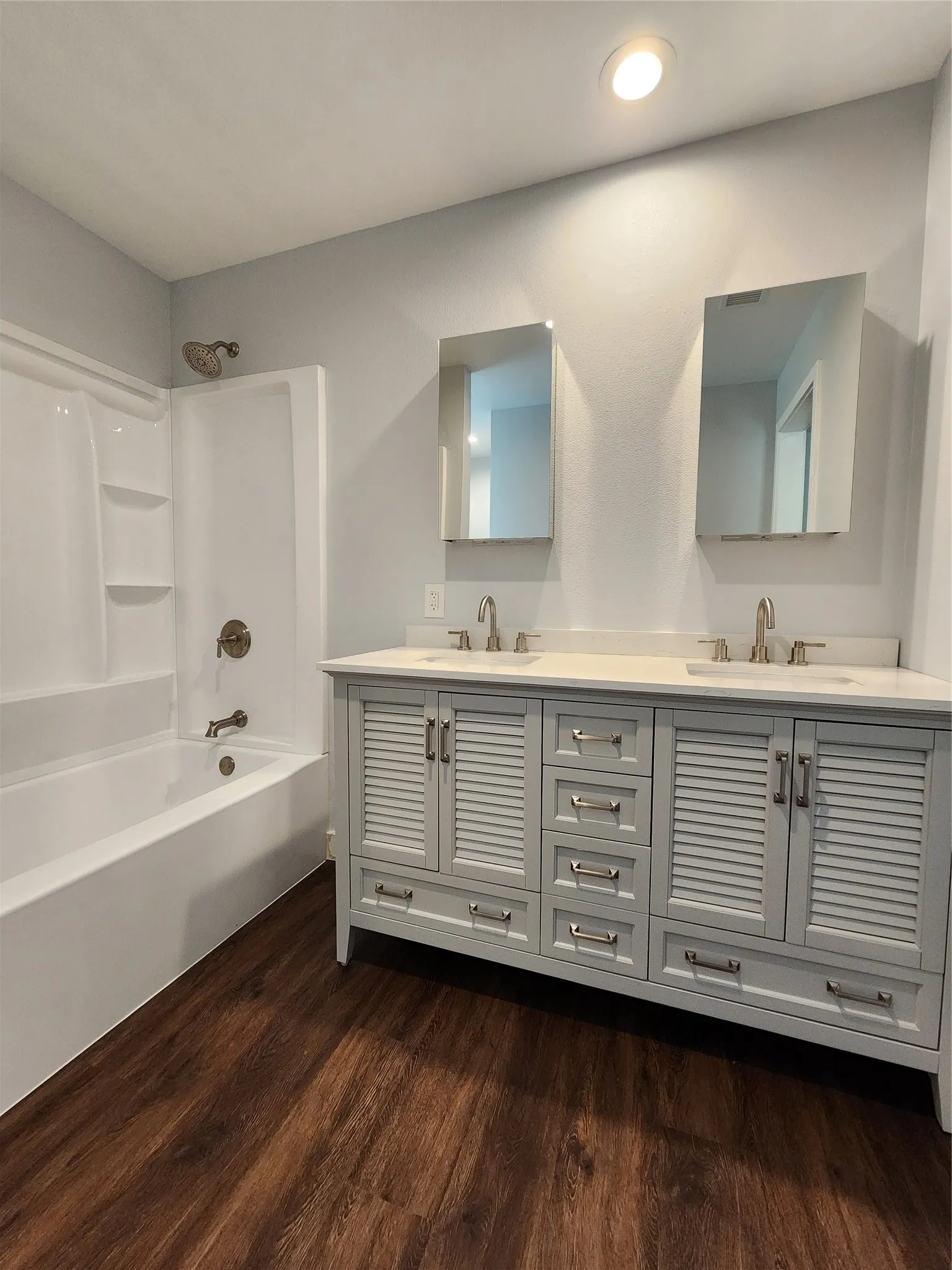 Primary bathroom featuring double vanity with louvered cabinetry, dual sinks, and brushed nickel fixtures
