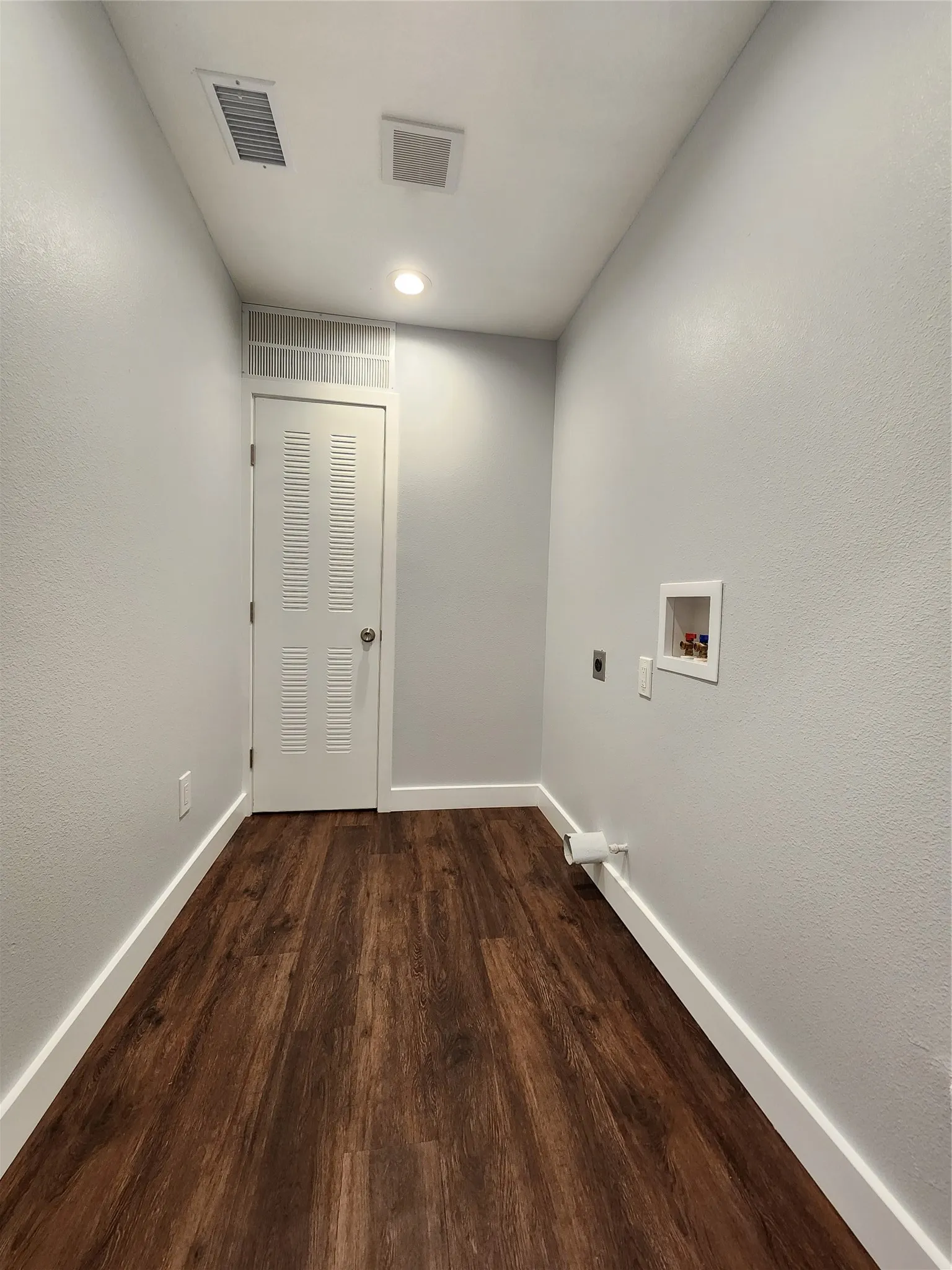 Neutral wall paint, wood-finish flooring, white trim, recessed lighting, and a louvered door
