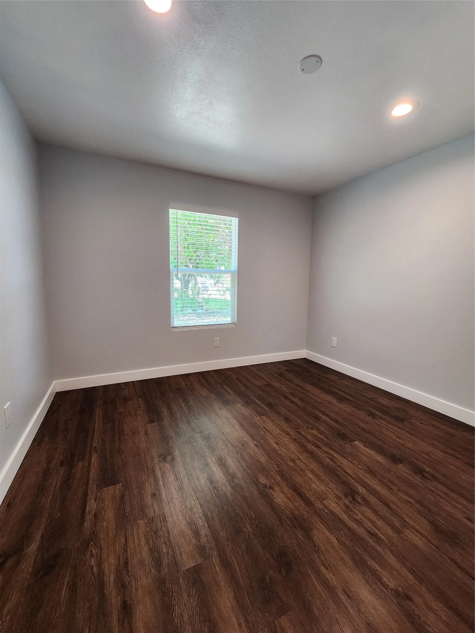 Hardwood-look flooring, recessed lighting, and a window with blinds