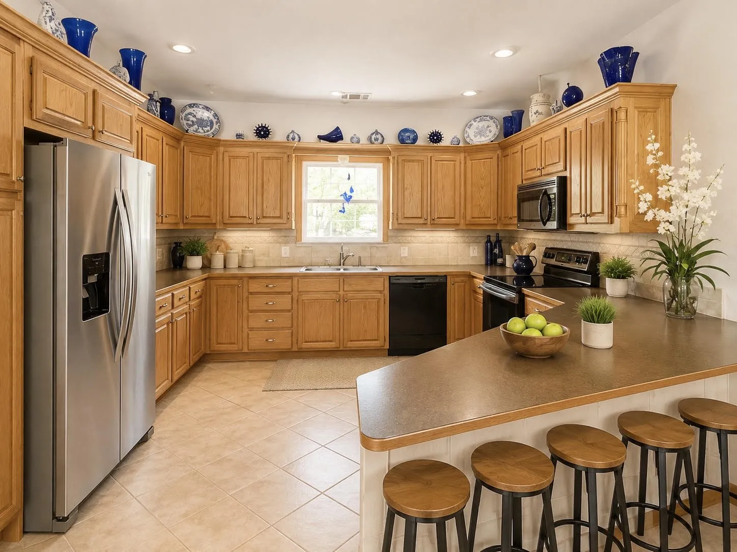 U-shaped kitchen featuring wood cabinetry, stainless steel refrigerator, black range, integrated microwave, and a breakfast bar with built-in paneling