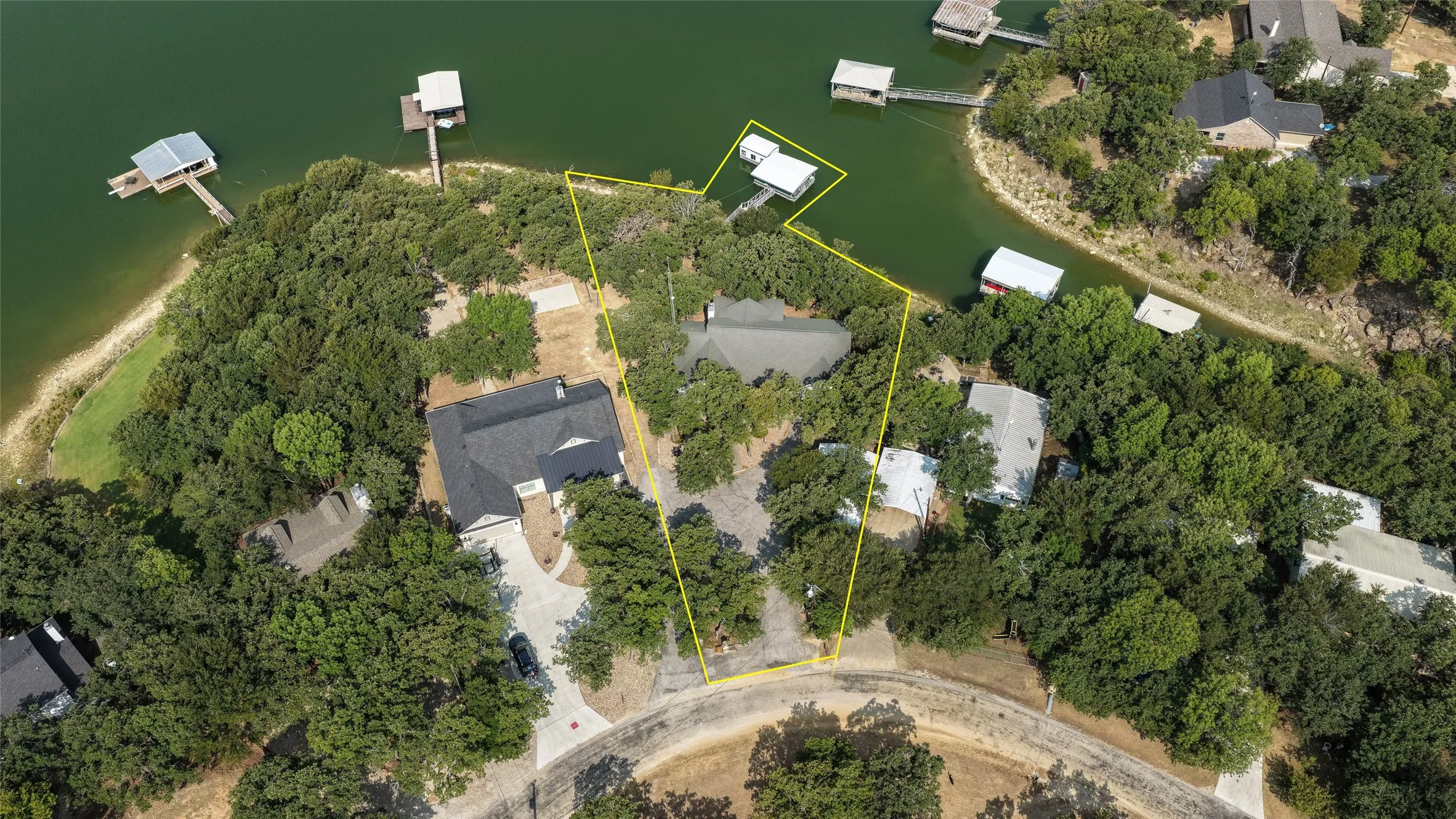Aerial property featuring mature trees and waterfront access with multiple docks
