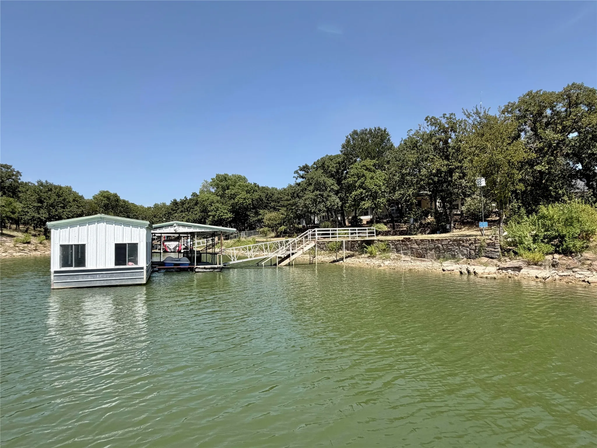 Private boat dock with covered slip, floating structure, and direct access to the water