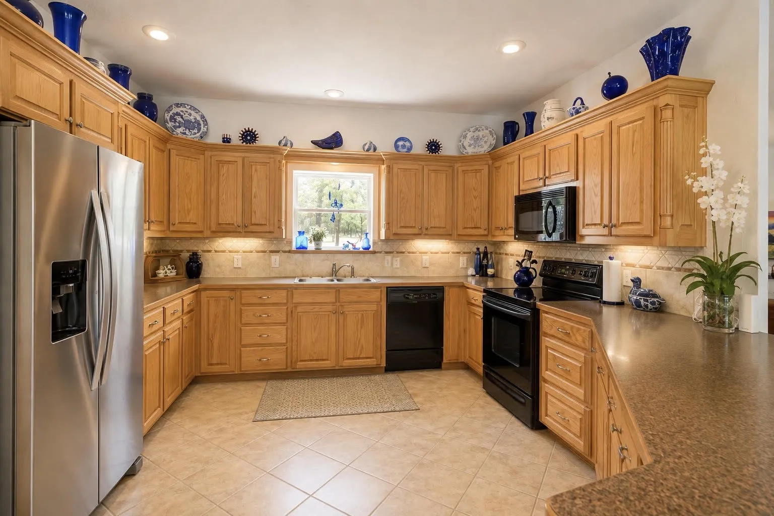 Kitchen featuring wood cabinetry, stainless steel refrigerator, black built-in appliances, recessed lighting, and tile flooring