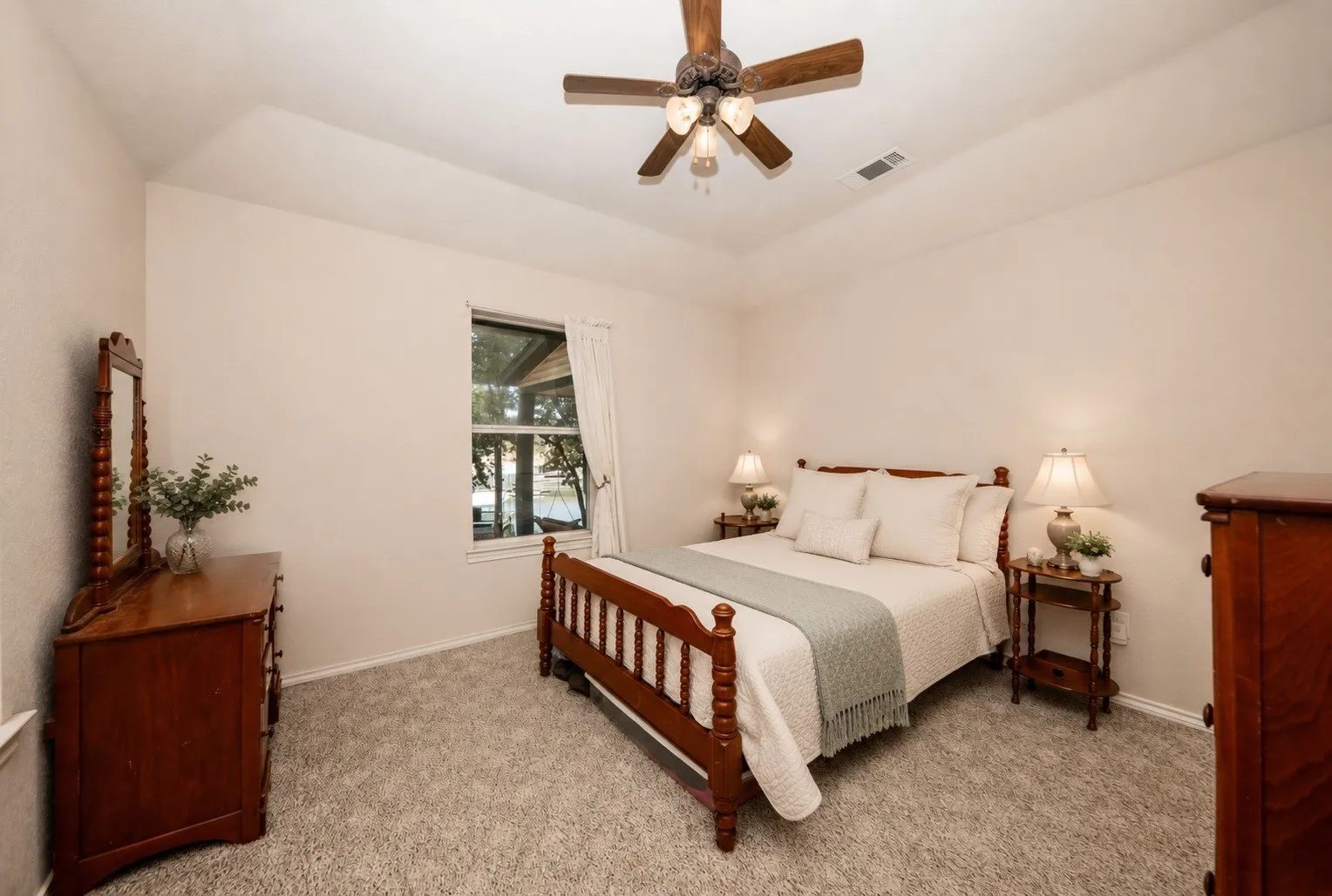 Tray ceiling with a decorative ceiling fan, wall-to-wall carpeting, and a window with exterior views
