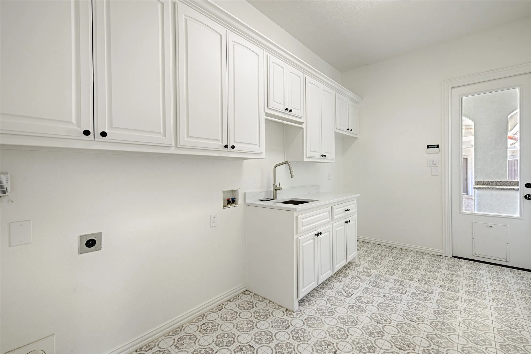 Laundry room featuring hookup for an electric dryer, a sink, hookup for a washing machine, baseboards, and cabinet space