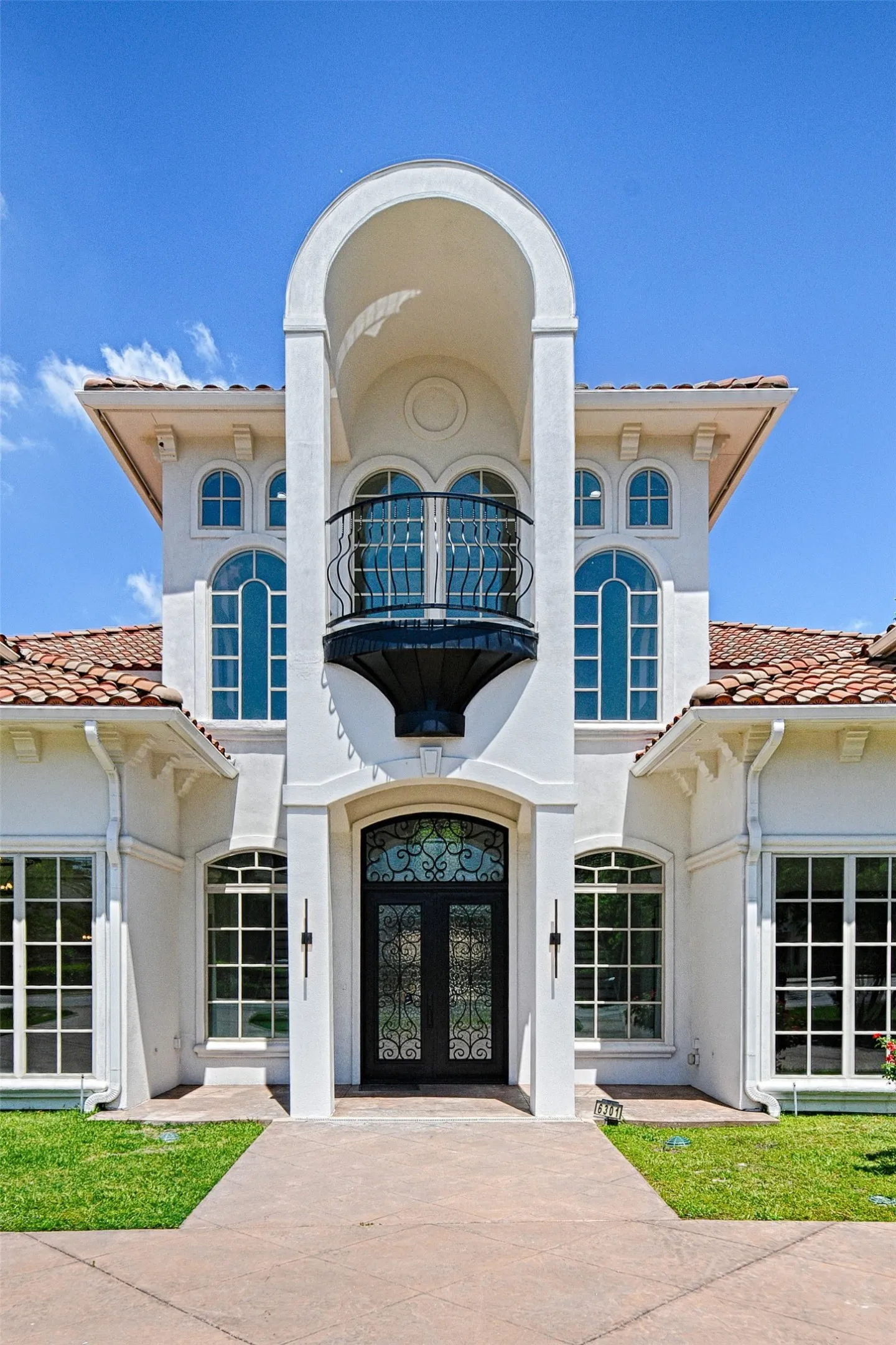 View of front of property featuring a tile roof, french doors, a balcony, and stucco siding
