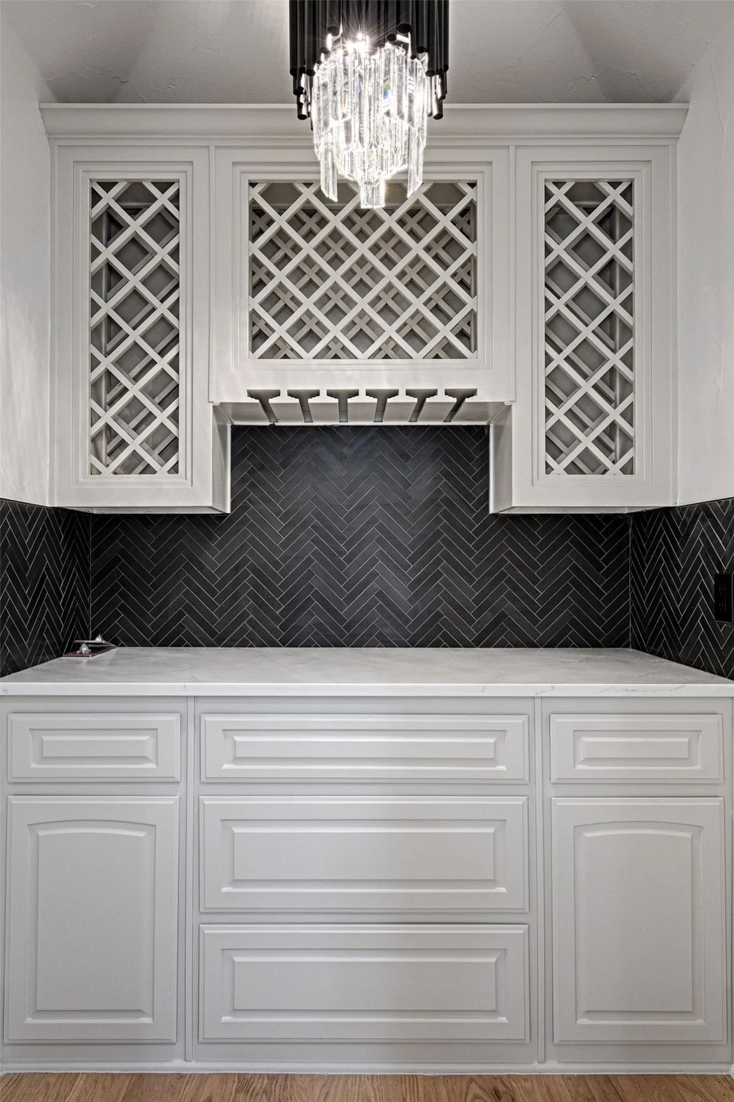 Bar with tasteful backsplash, pendant lighting, and an inviting chandelier