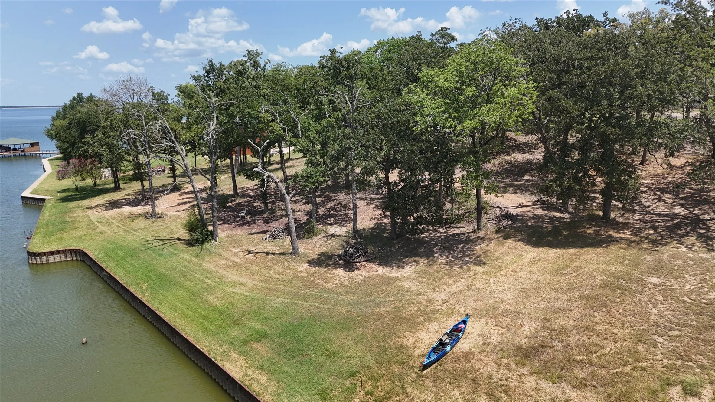 Waterfront perspective showcases the wooded setting and steel retaining wall surrounding this nearly one-acre Richland Chambers Lake property.