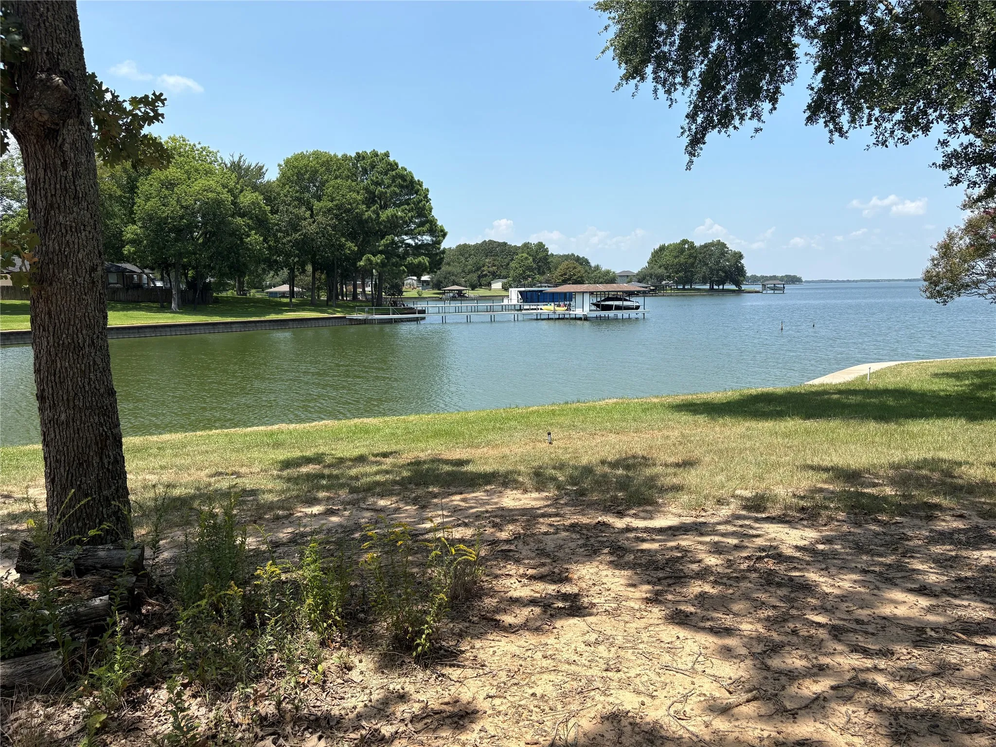 Beautiful lake view through mature trees demonstrates the relaxing waterfront setting along Cambridge Drive in Streetman.