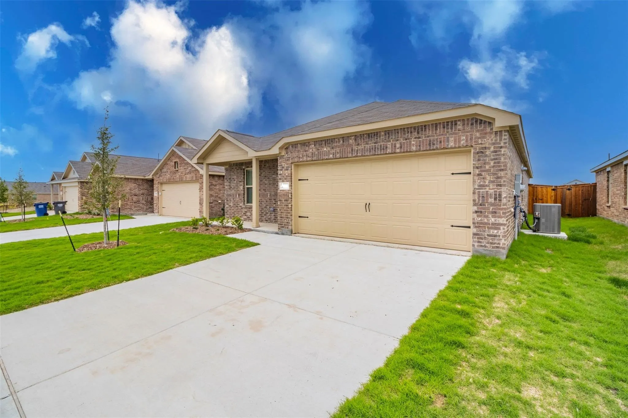 Brick exterior with a two-car garage, concrete driveway, and a manicured lawn