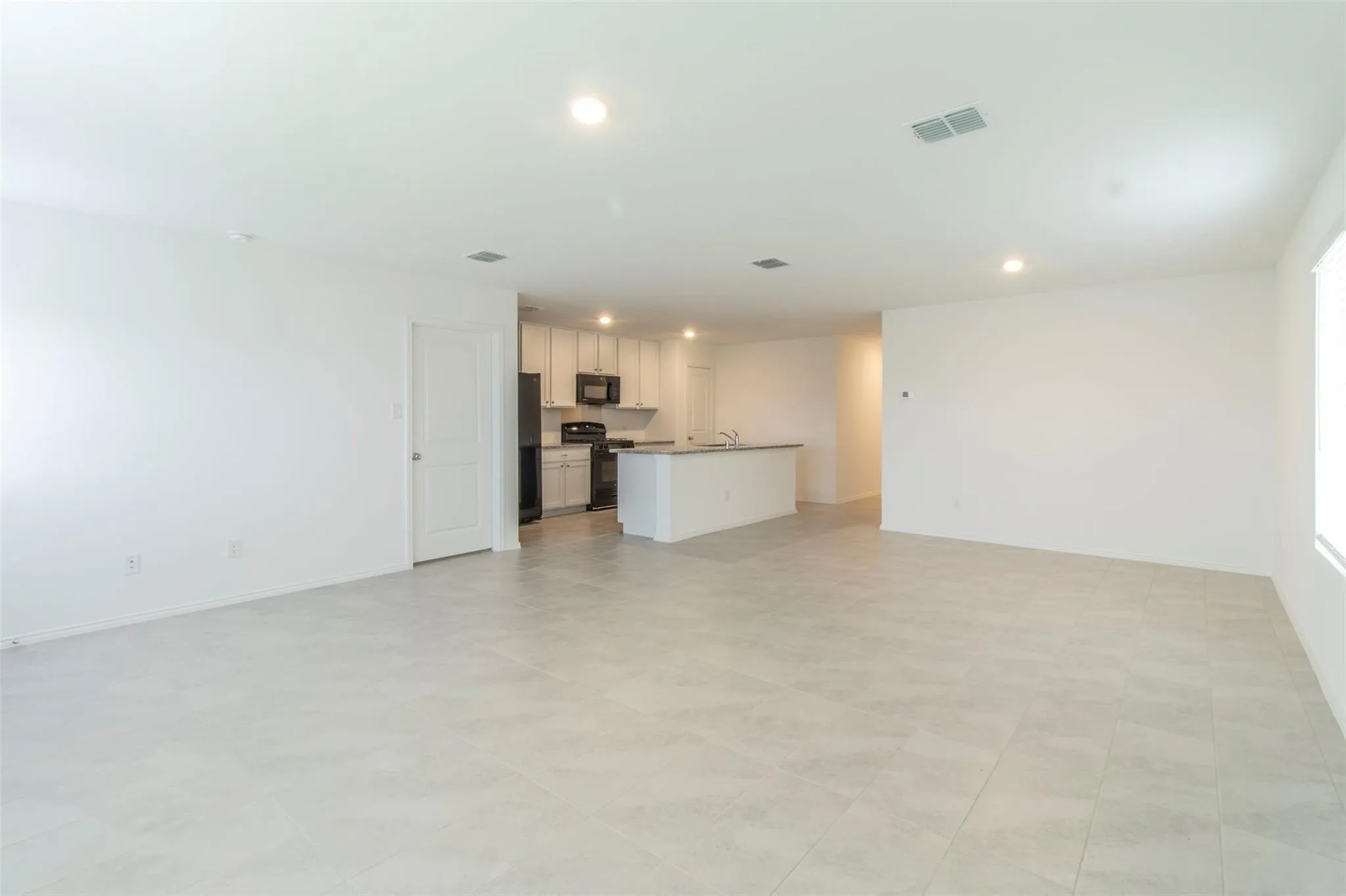 Open-concept living area with light-colored tile flooring and recessed lighting