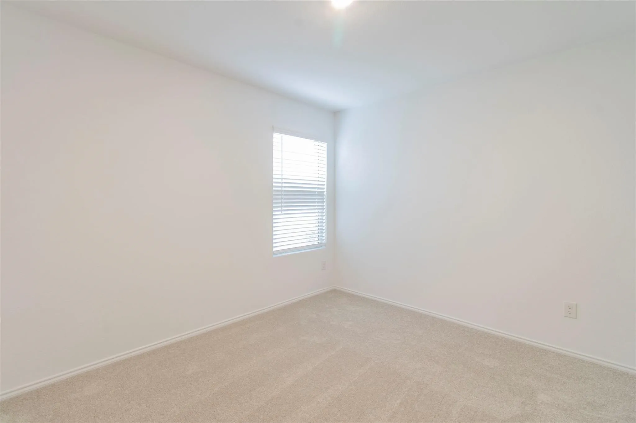 Neutral wall tones, recessed lighting, and a single window with blinds