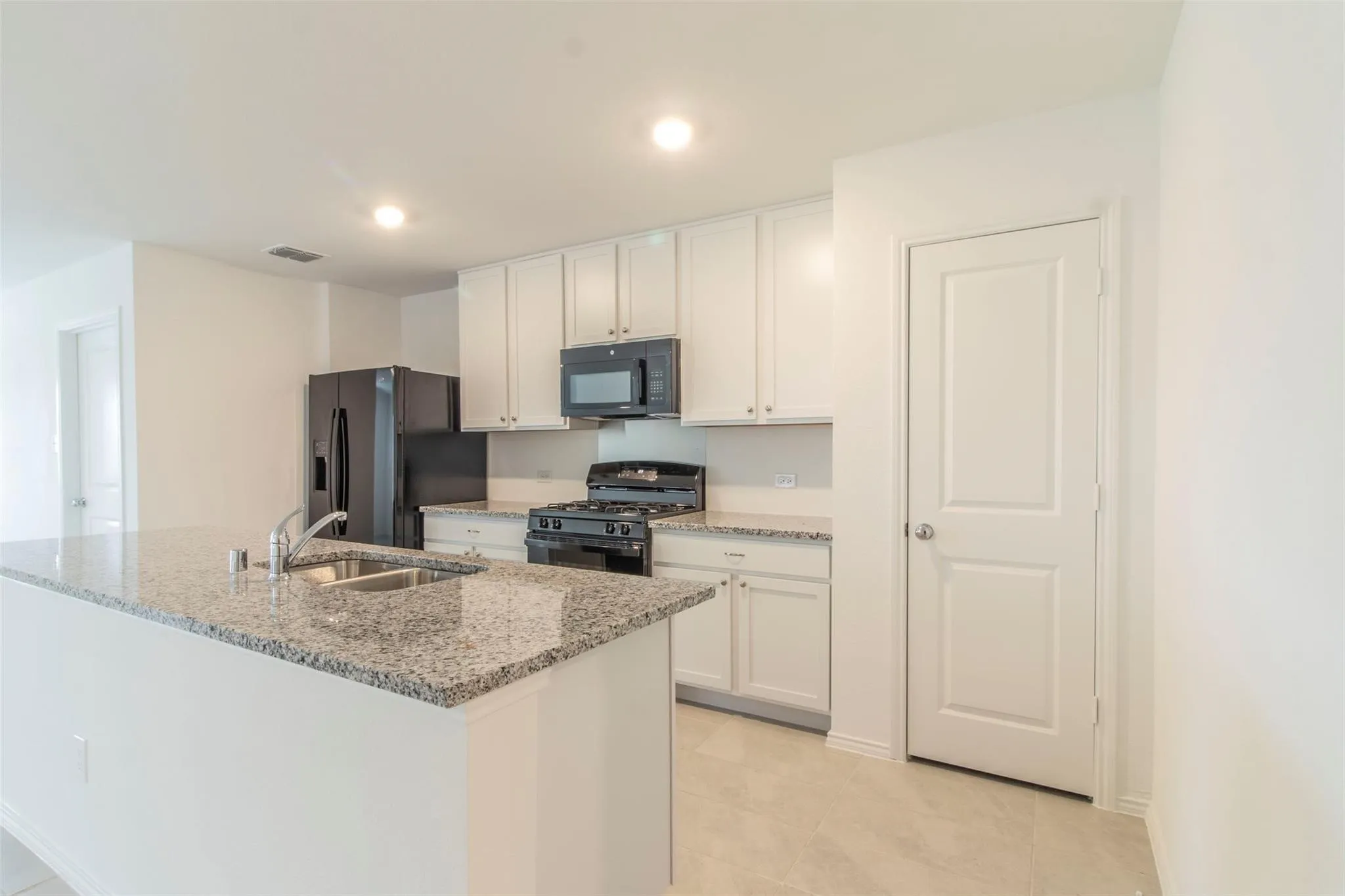 Kitchen featuring white cabinetry, granite countertops, stainless steel sink, and recessed lighting