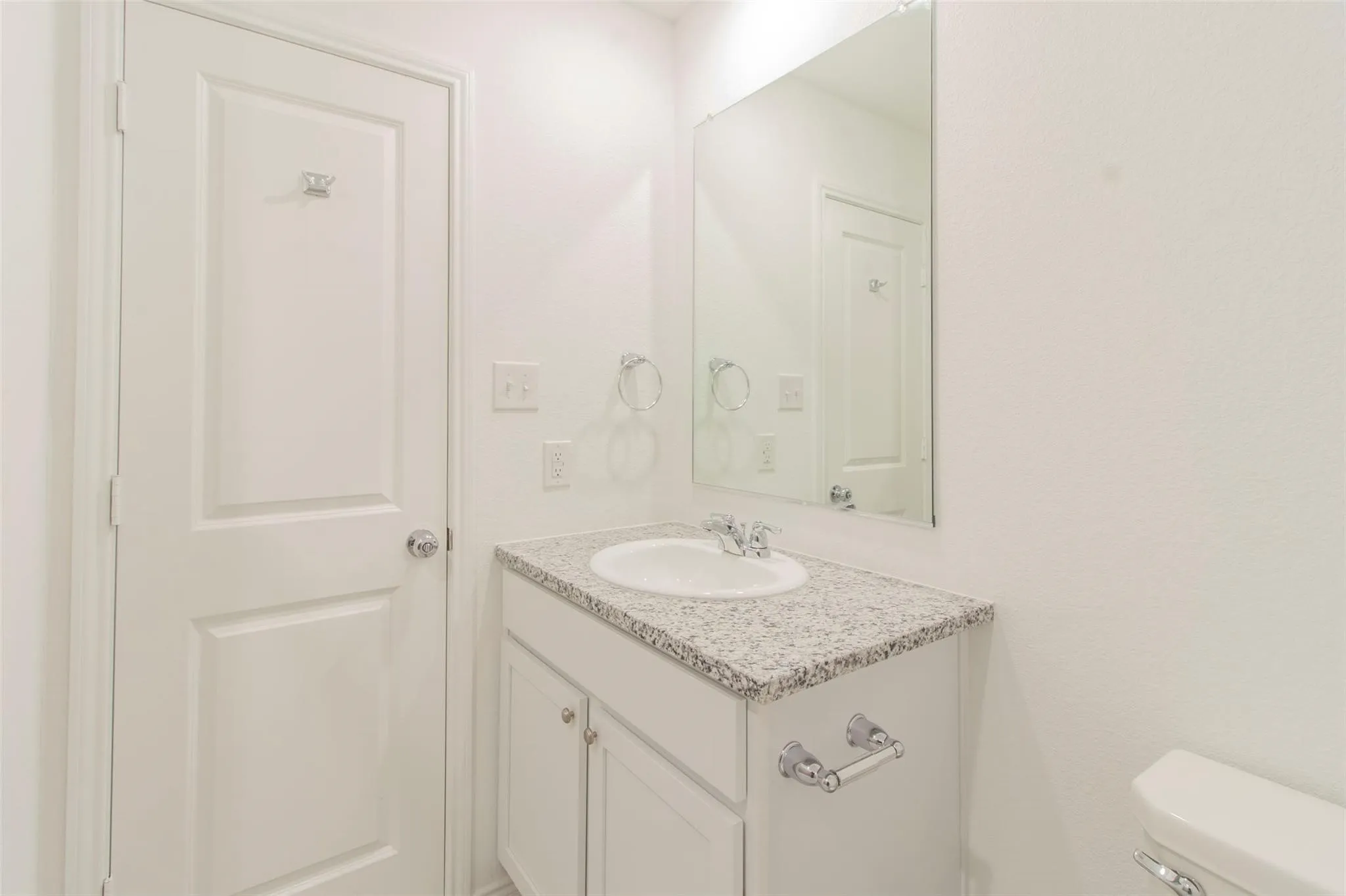 Vanity with an integrated sink, polished chrome faucet, and a light-toned speckled countertop