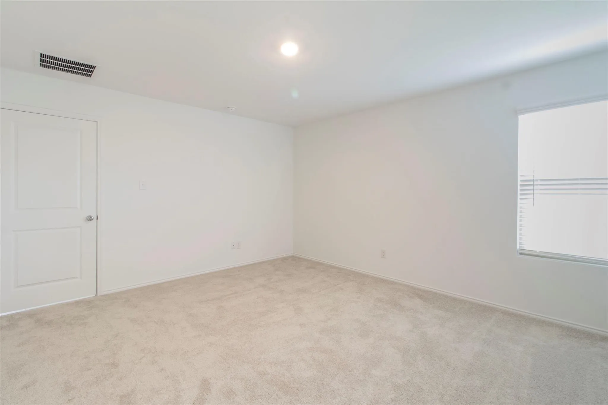 Wall-to-wall carpeting, recessed ceiling lighting, and a window with horizontal blinds