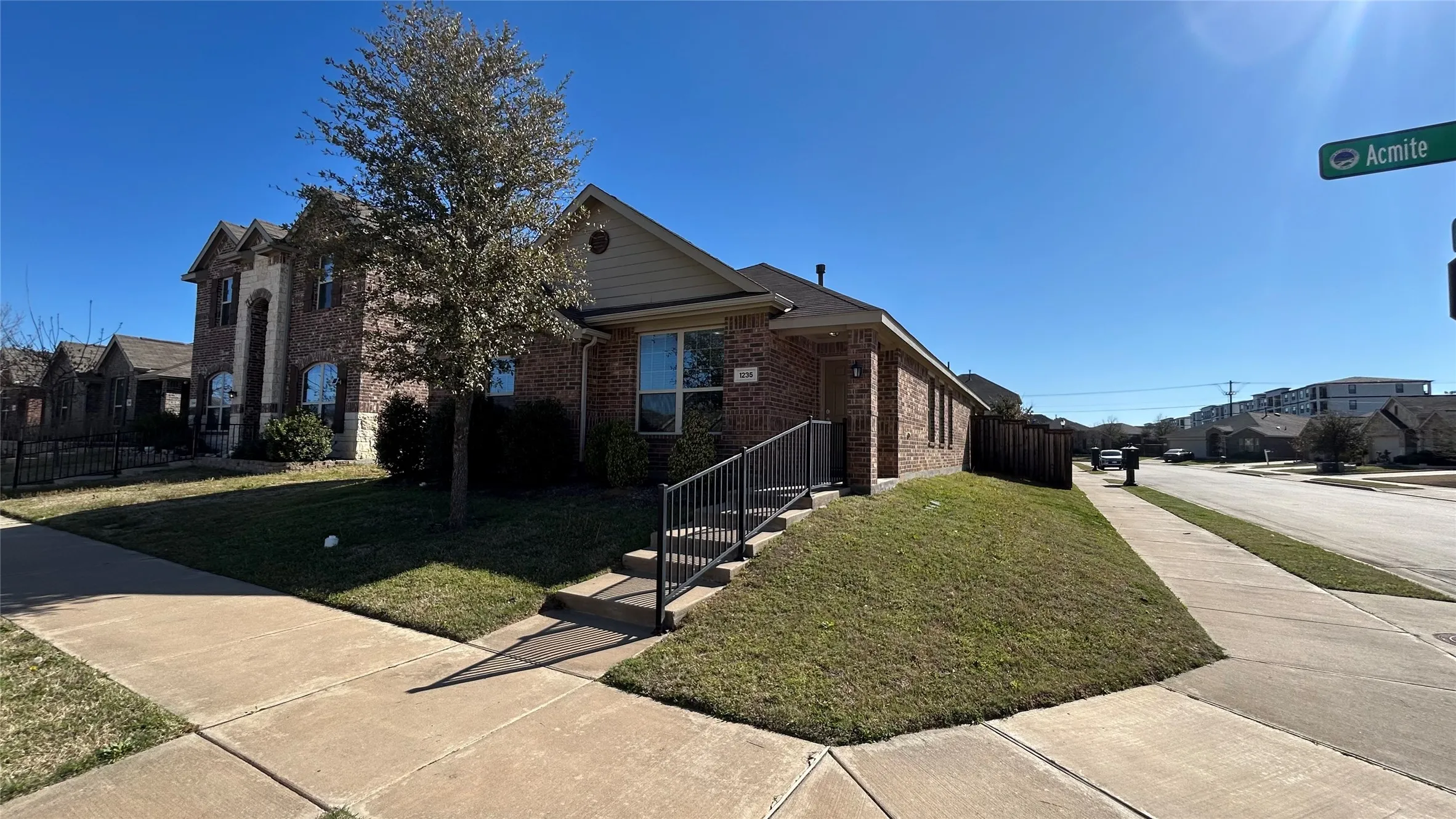 Brick exterior with stone accents, a concrete walkway, and a sloped grassy area