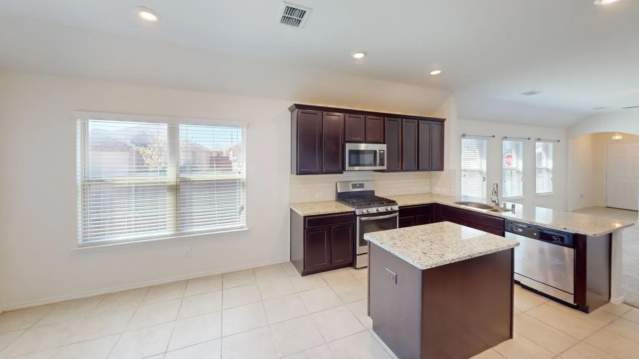 Kitchen featuring dark wood cabinetry, light countertops, stainless steel appliances, and tile flooring