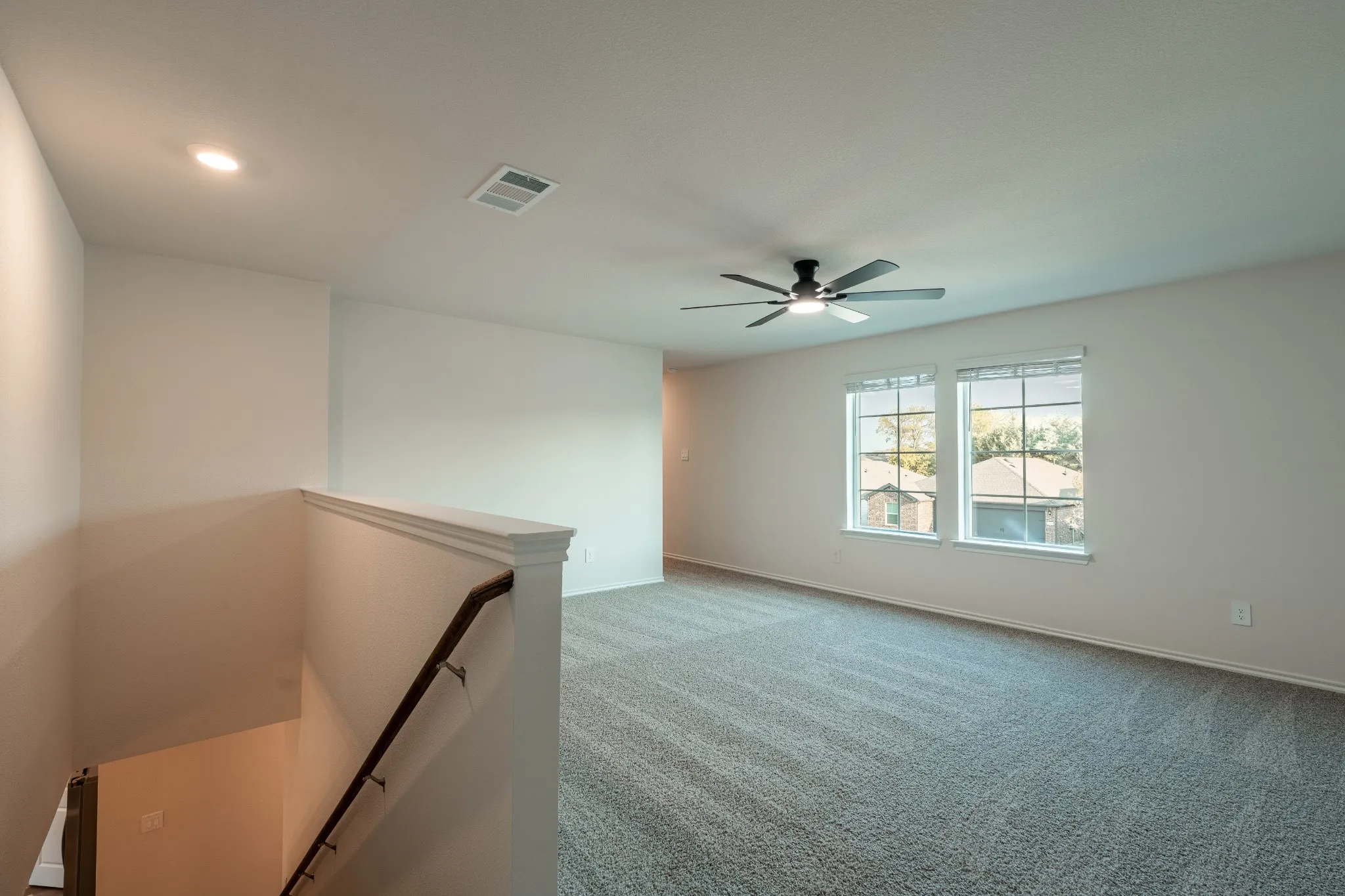 Spacious game room/living space on second floor with plenty of  natural light and newly installed ceiling fan.