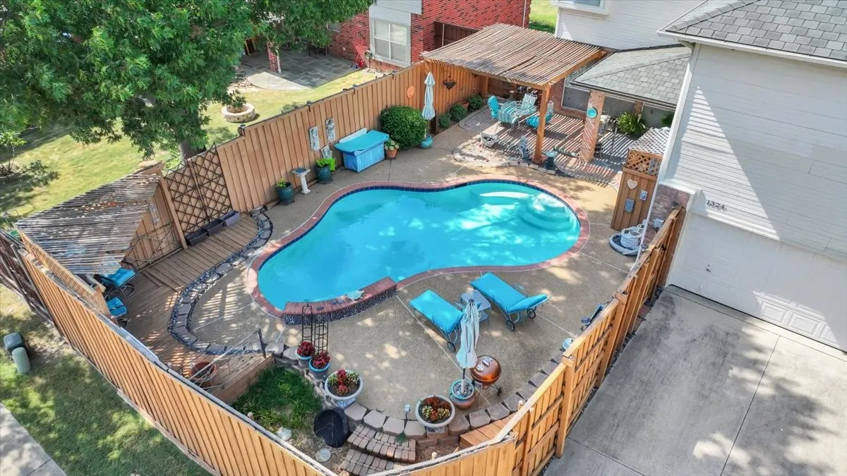 Kidney-shaped swimming pool with integrated steps, surrounded by a concrete patio
