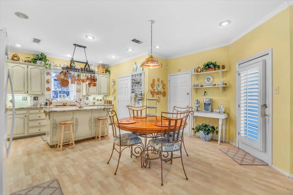 Kitchen with light-toned wood-finish flooring, white cabinetry, and granite countertops