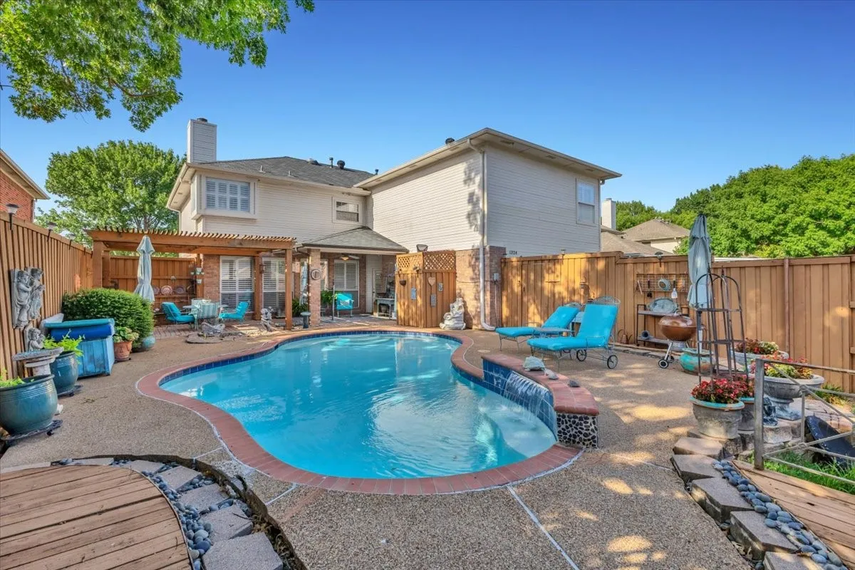 Outdoor swimming pool with a curved perimeter and integrated waterfall feature