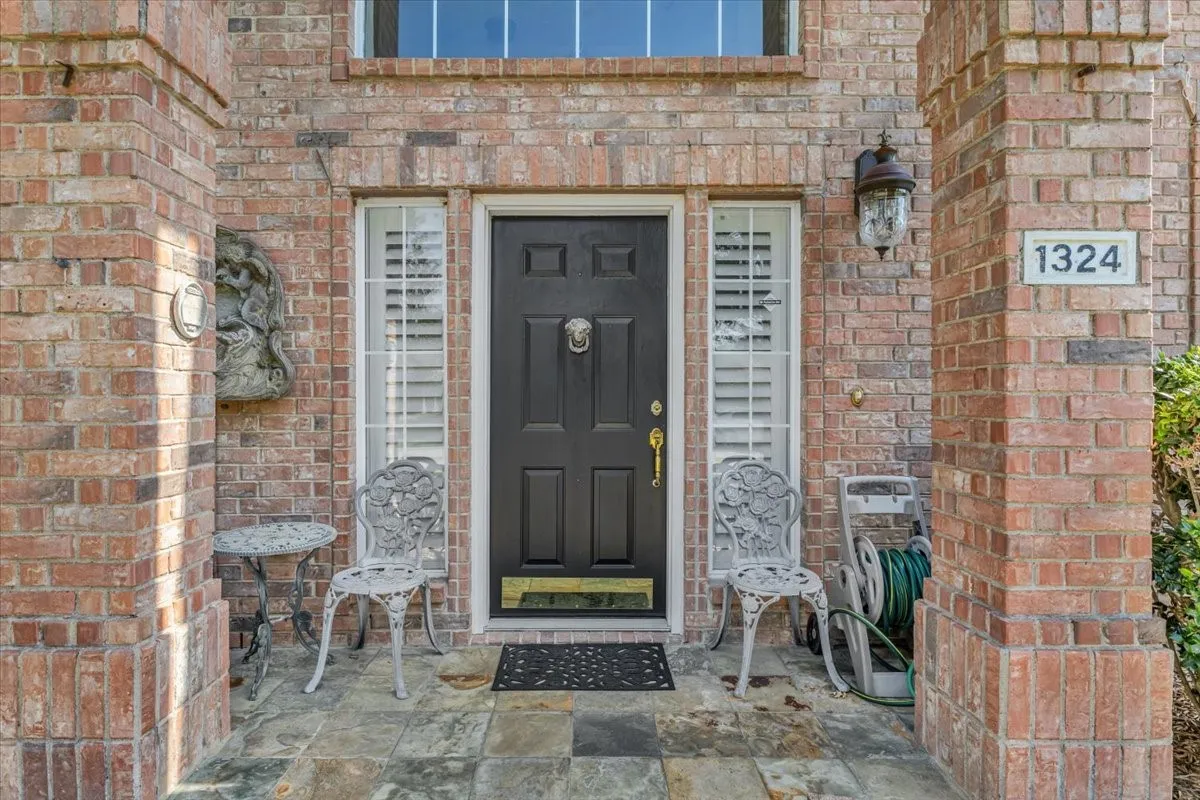 Brick facade featuring a panel door, transom window, and shuttered sidelights