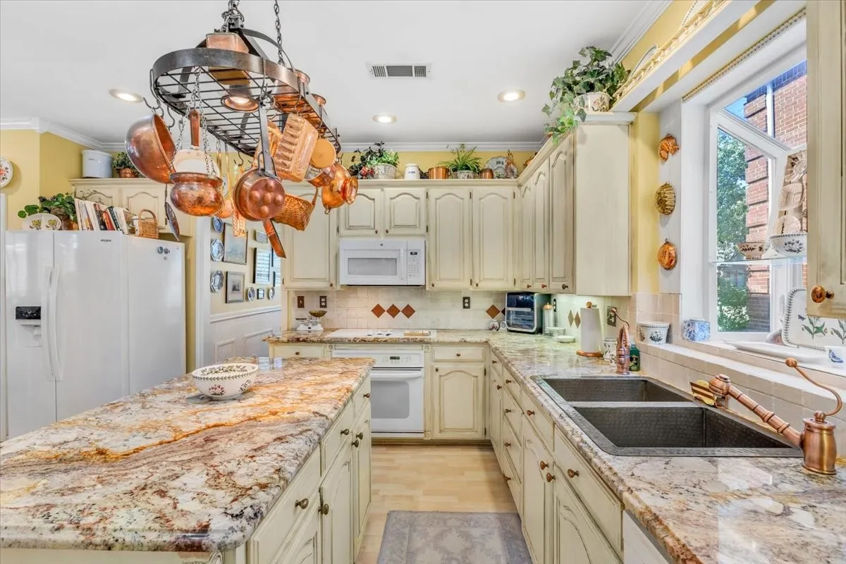 Kitchen featuring a central island with a stone surface, extensive cabinetry, dual basin sink, and a built-in oven with overhead microwave