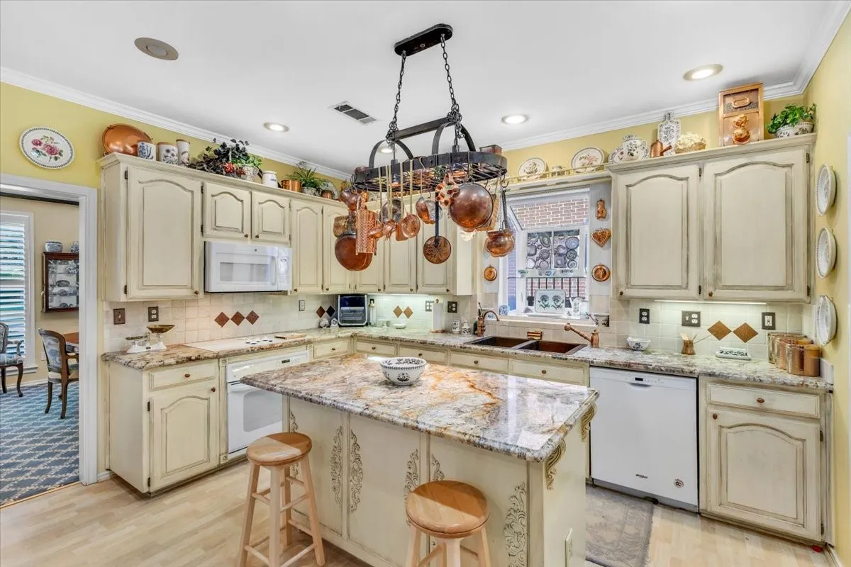 Kitchen featuring wood-finish flooring, an island with a stone countertop, built-in cabinetry, an integrated microwave, and a double-basin sink