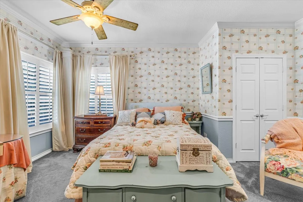 Recessed bay windows with plantation shutters, ceiling fan with integrated lighting, wall-to-wall carpeting, and dual-panel closet doors