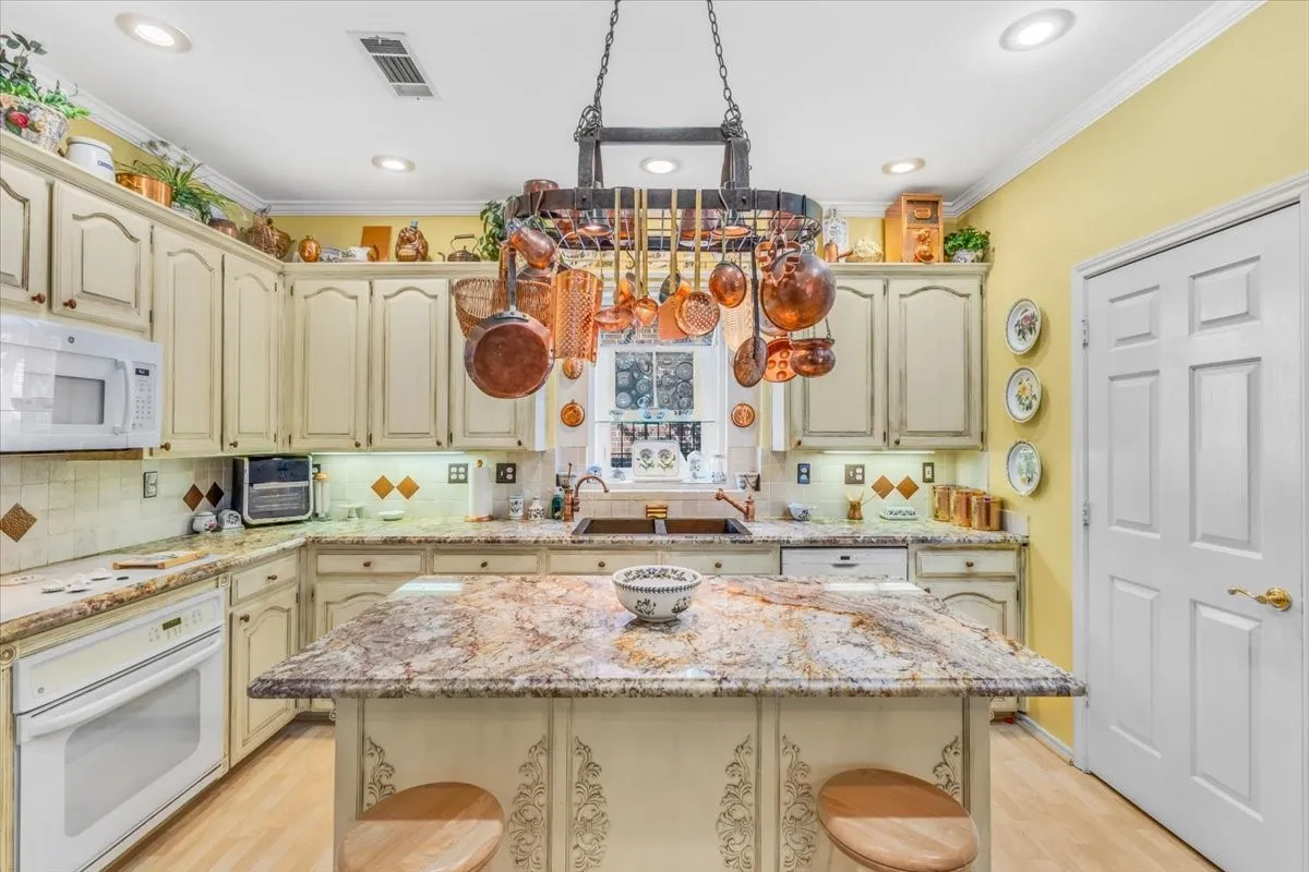 Kitchen featuring a central island with a stone countertop, painted cabinetry, a tile backsplash, and recessed lighting