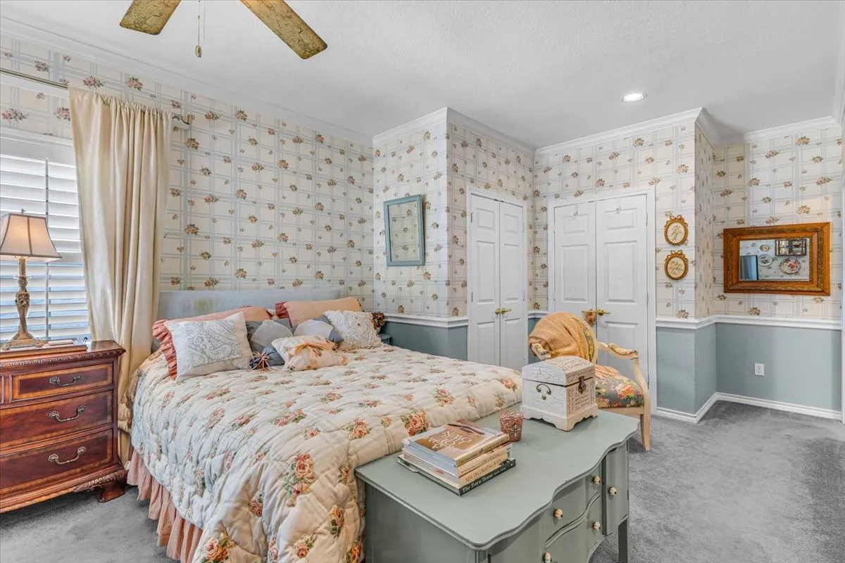 Ceiling fan with light fixture, plantation shutters, crown molding, chair rail molding, and multiple paneled closet doors