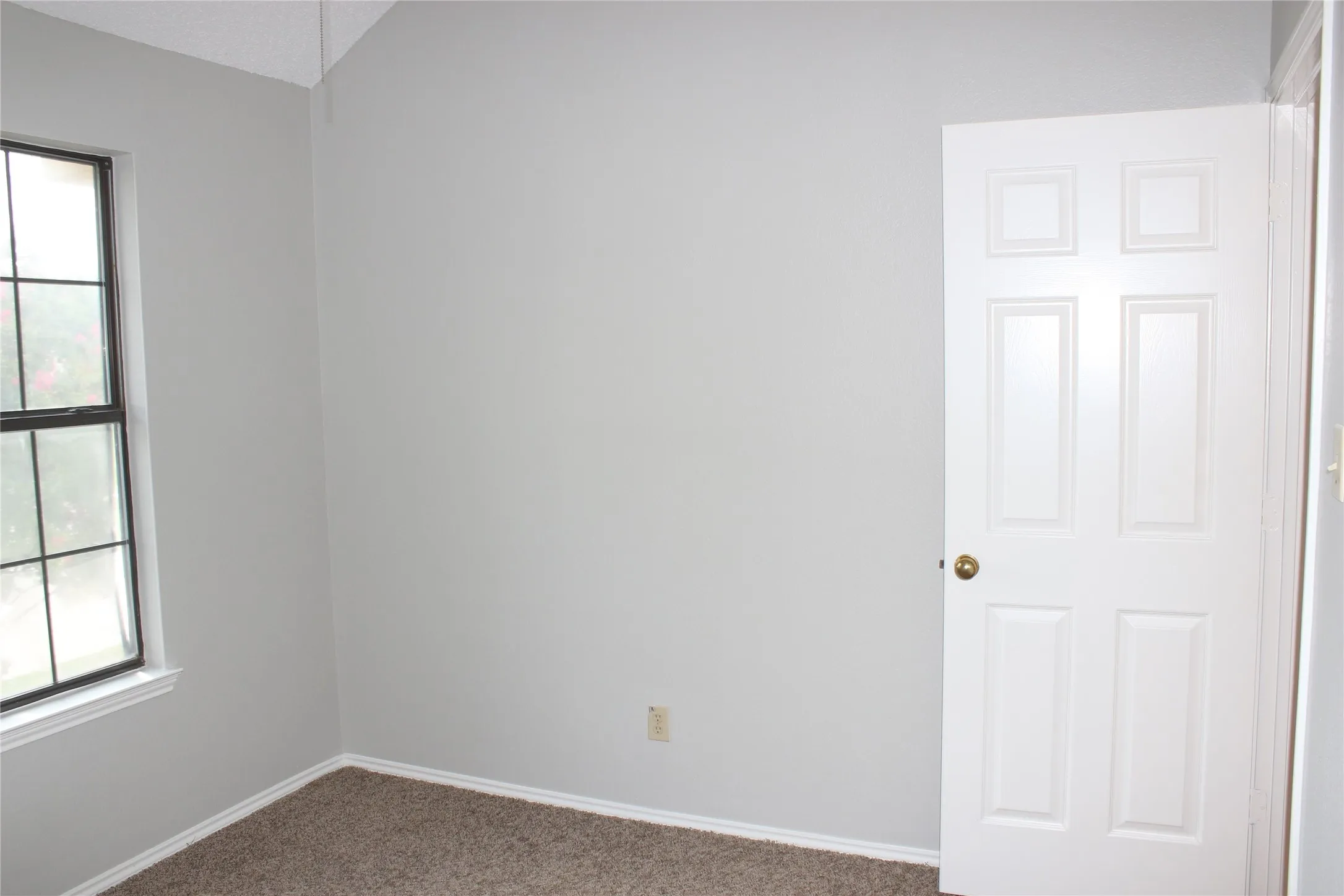 Interior room with light gray walls, textured carpet flooring, and a vaulted ceiling