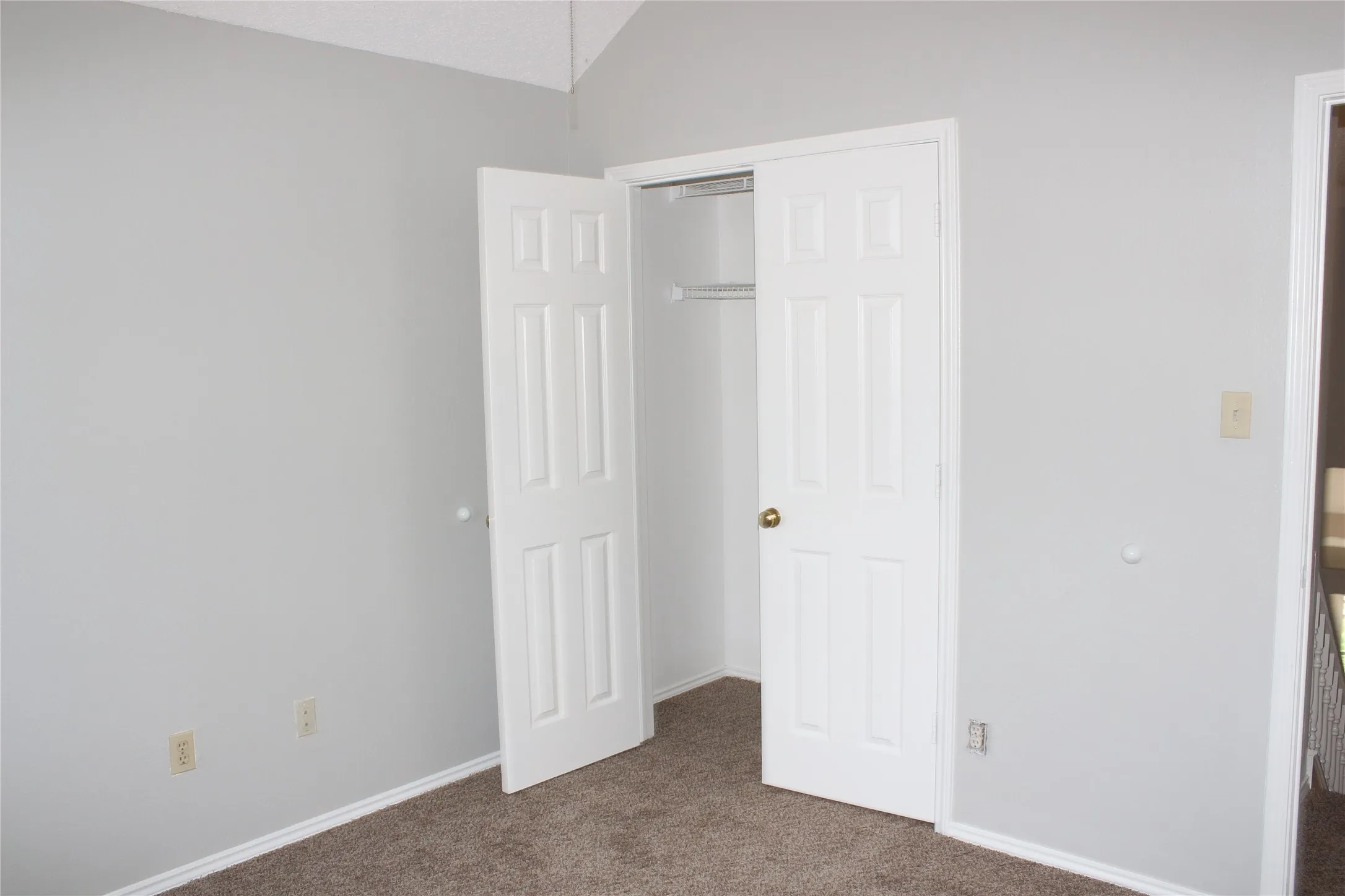 Bedroom featuring a vaulted ceiling, light gray wall paint, and plush carpet flooring