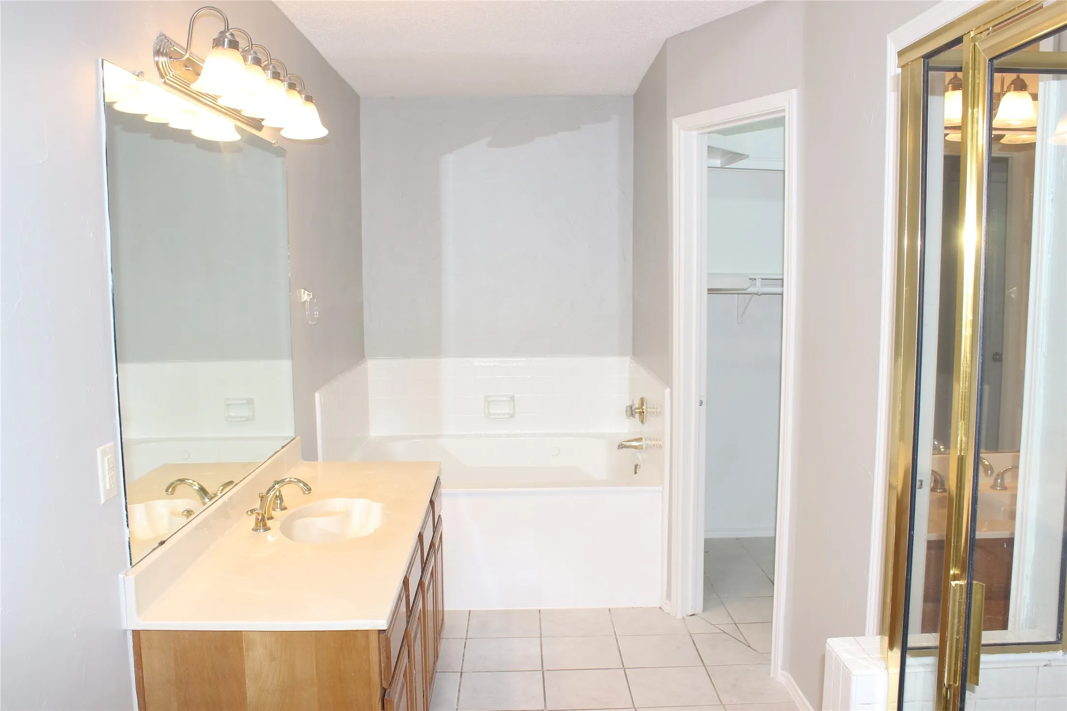 Bathroom featuring a single vanity with wood-finish cabinetry, a light-colored countertop, and a large wall mirror