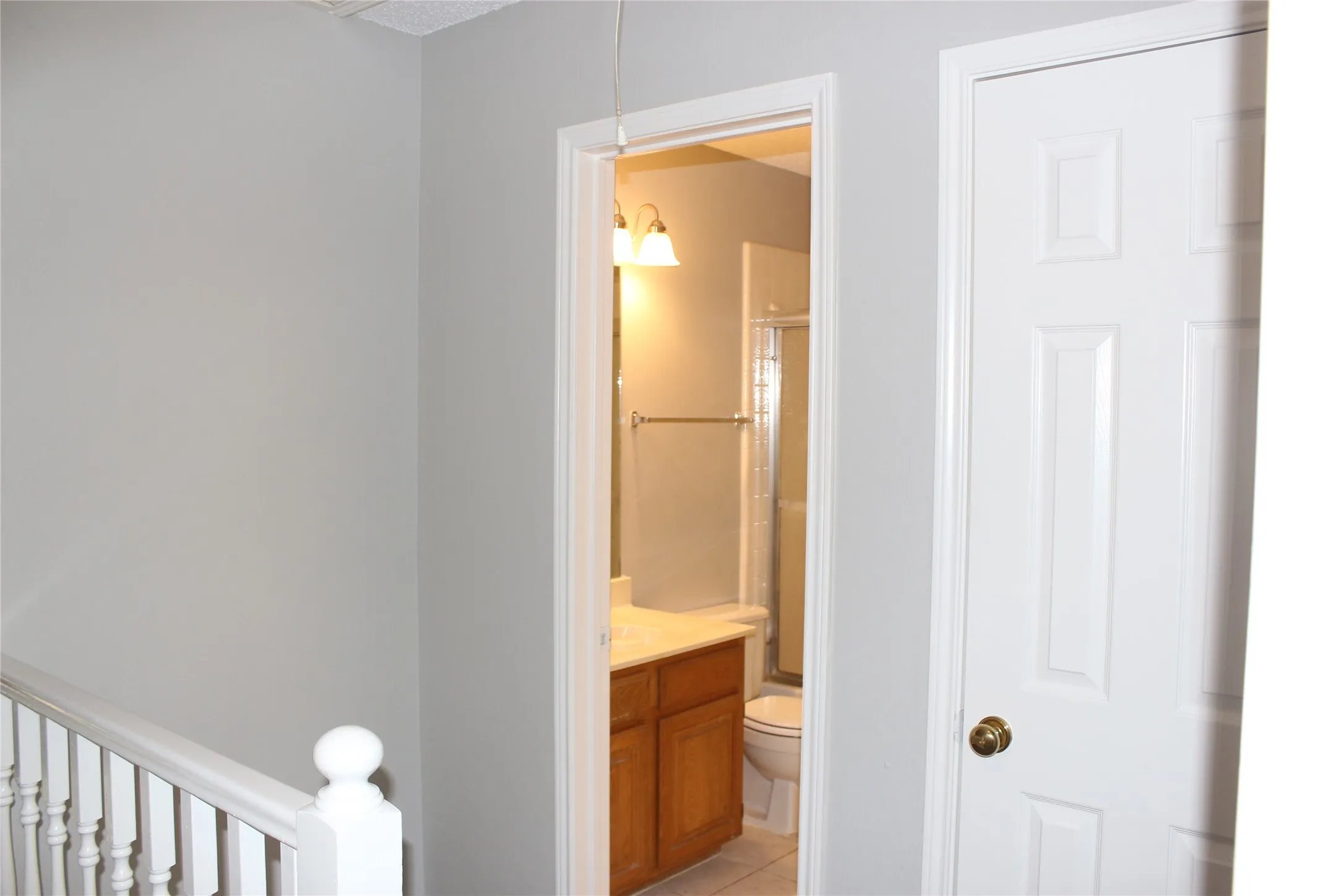 Full bathroom featuring a wood-finish vanity, white countertop, and glass-enclosed shower