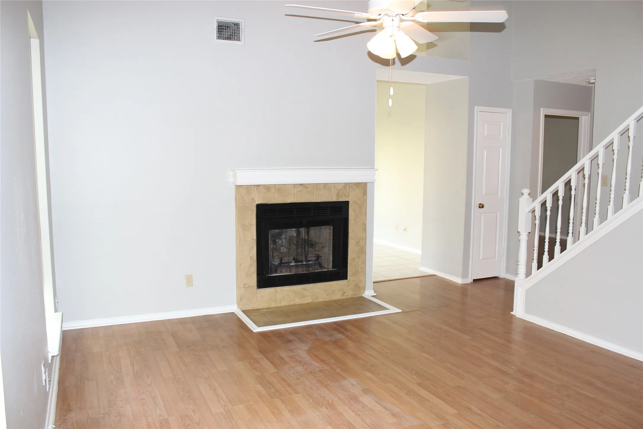 Living area featuring a fireplace with a tile surround and mantel, wood-finish flooring, and a ceiling fan