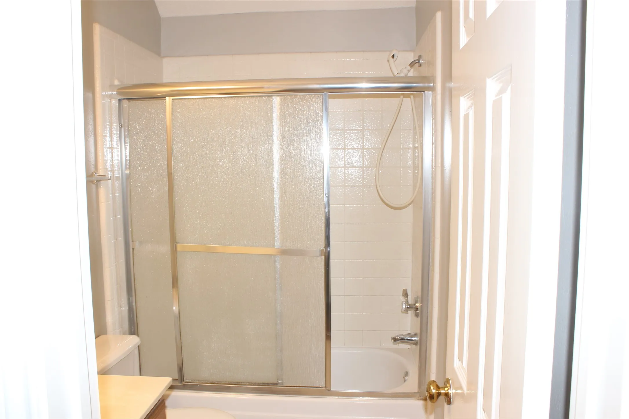 Bathroom featuring a tub/shower combination with sliding glass doors and white subway tile surround