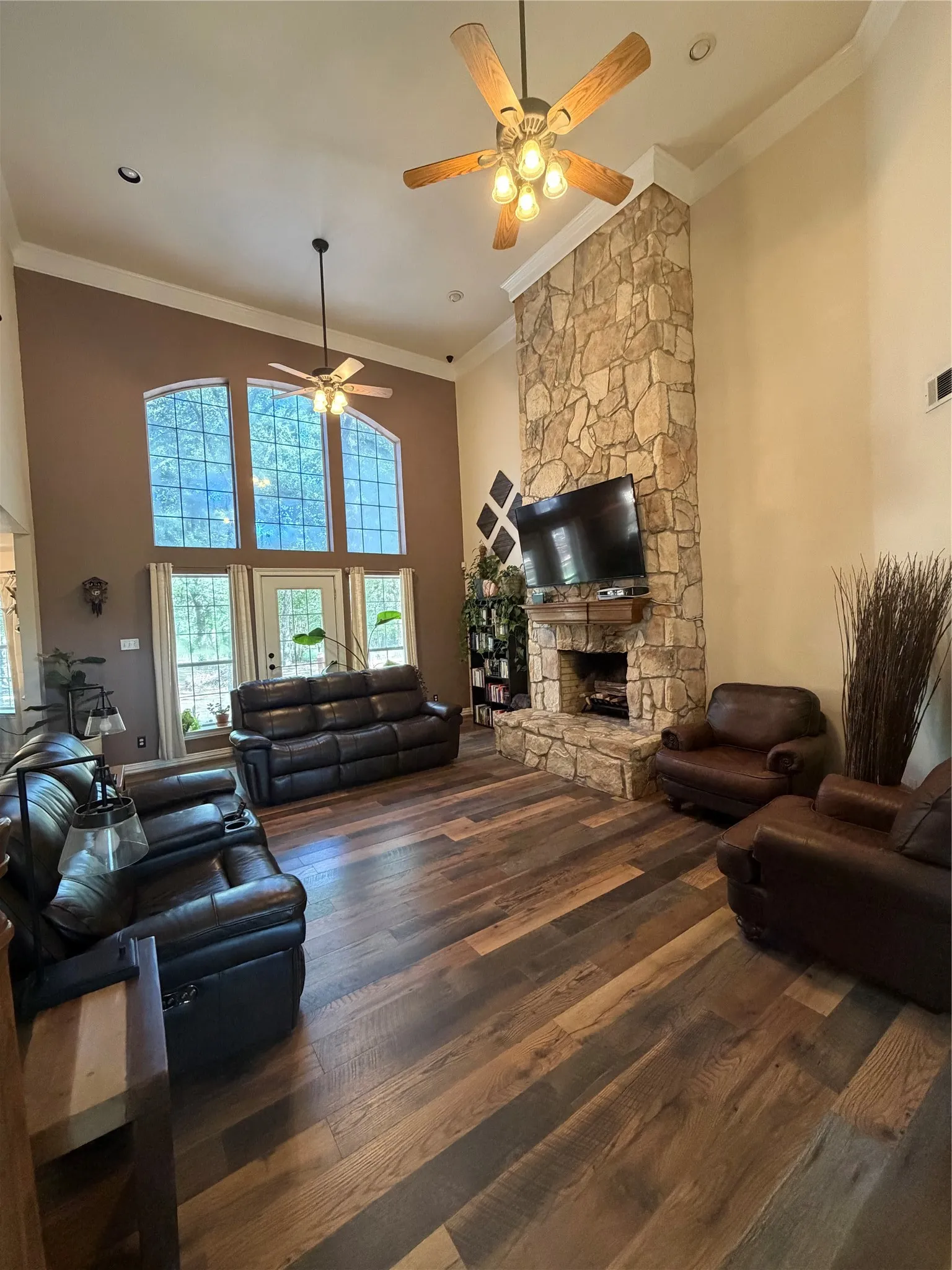 Vaulted ceilings, a floor-to-ceiling stone fireplace, and wood-finish flooring define this living area