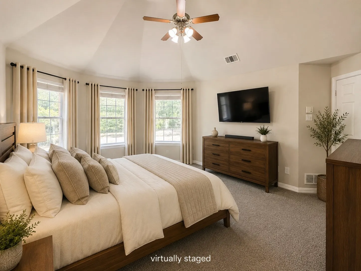 Elegant master bedroom. Vaulted ceiling with a ceiling fan, bay window with multiple windows, light-toned carpeting, and fresh neutral wall paint