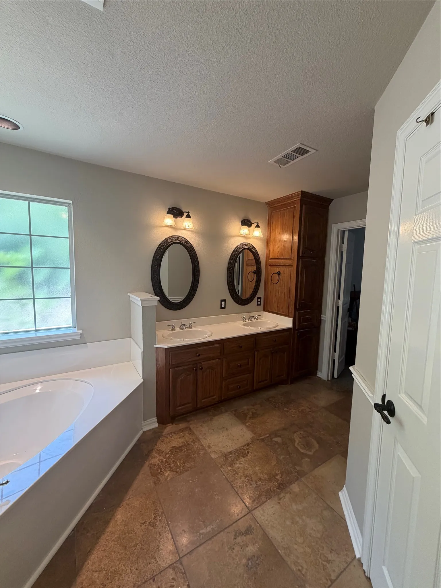 Master bath.  Freshly painted. Built-in soaking tub, dual vanity with undermount sinks, wood-finish cabinetry, and large format tile flooring